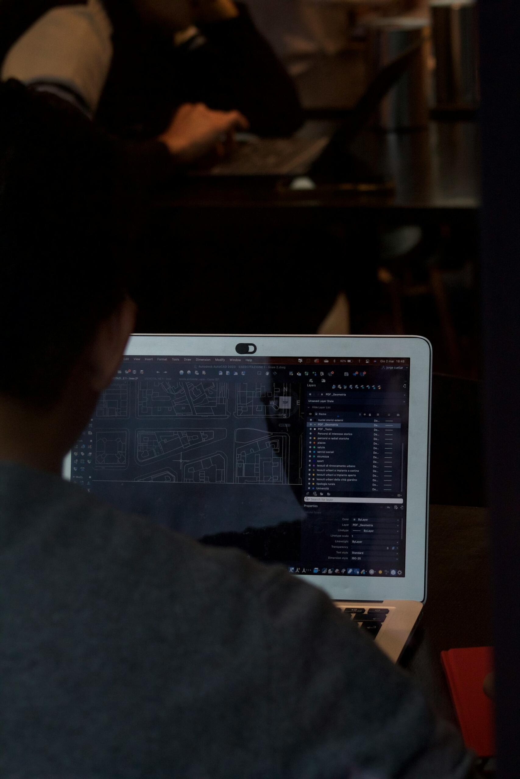 Człowiek patrzący na program AutoCAD na ekranie laptopa.