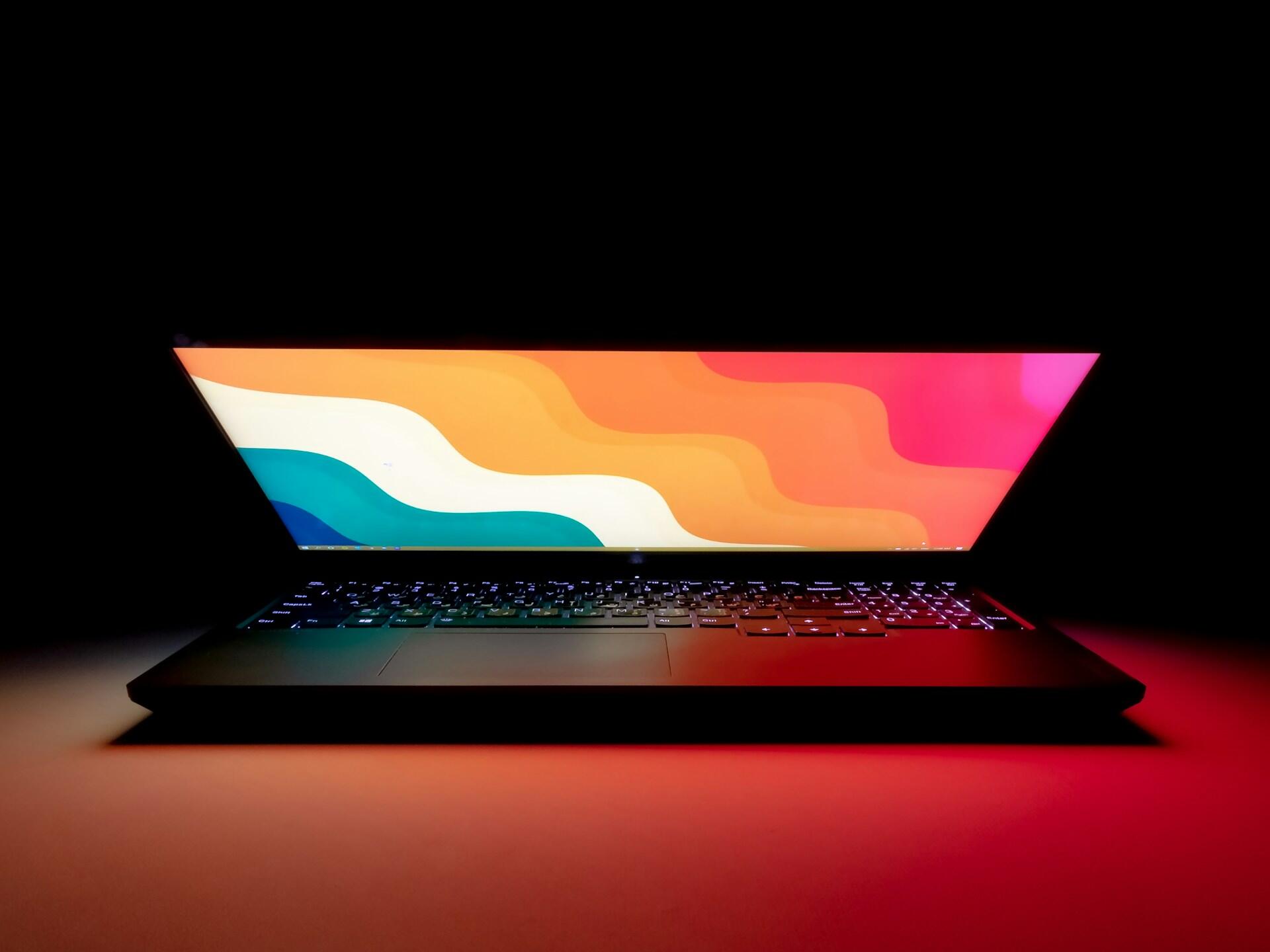 Przymknięty laptop z kolorową tapetą.