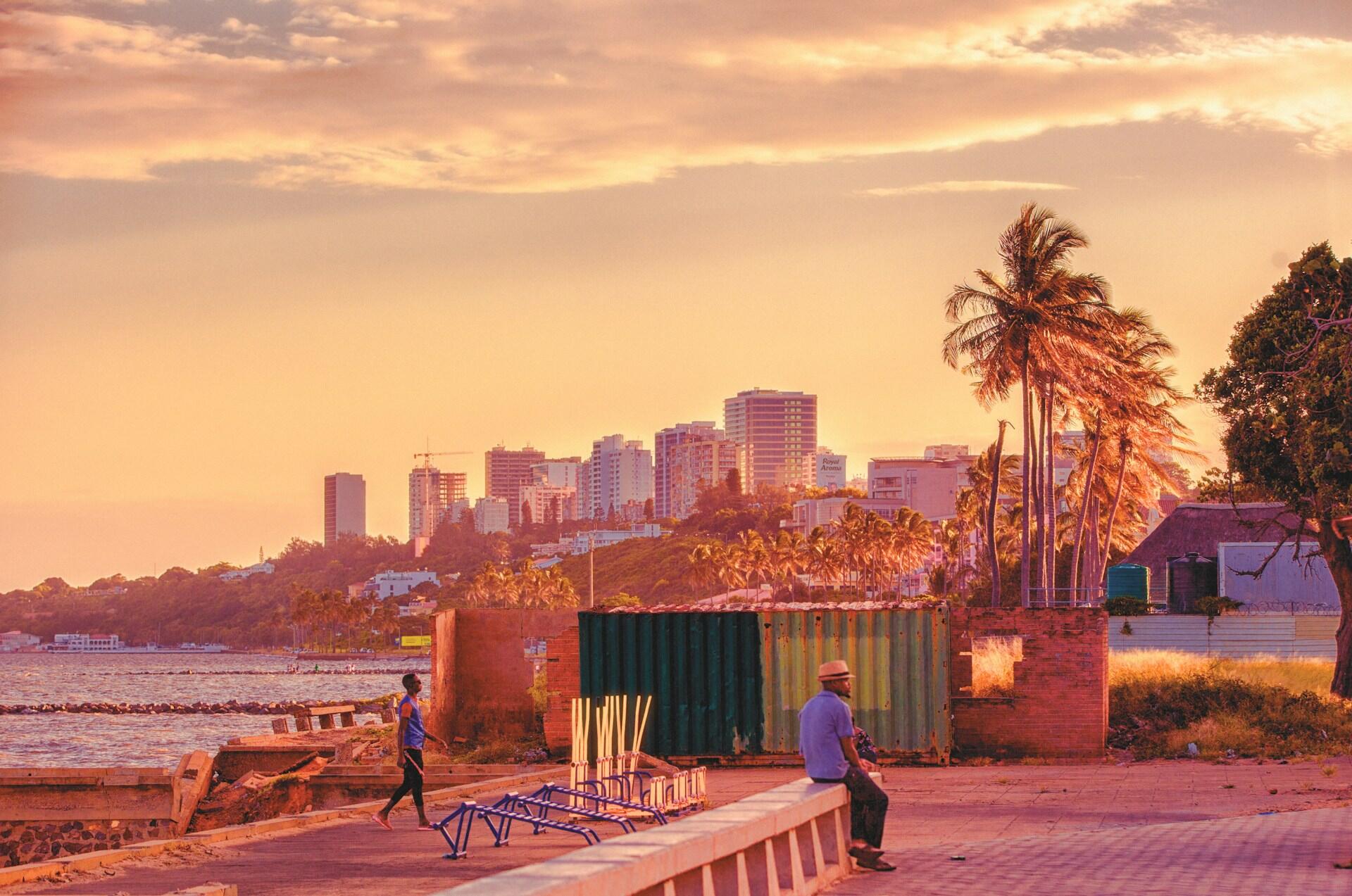 Maputo, Mozambik, zachód słońca na plaży z miastem i wieżowcami w tle.