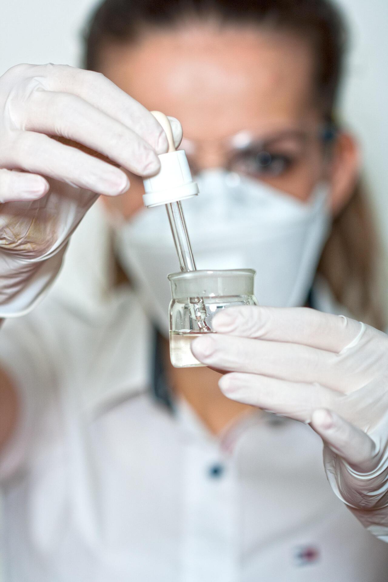Kobieta pobierająca pipetą płyn z pojemnika.