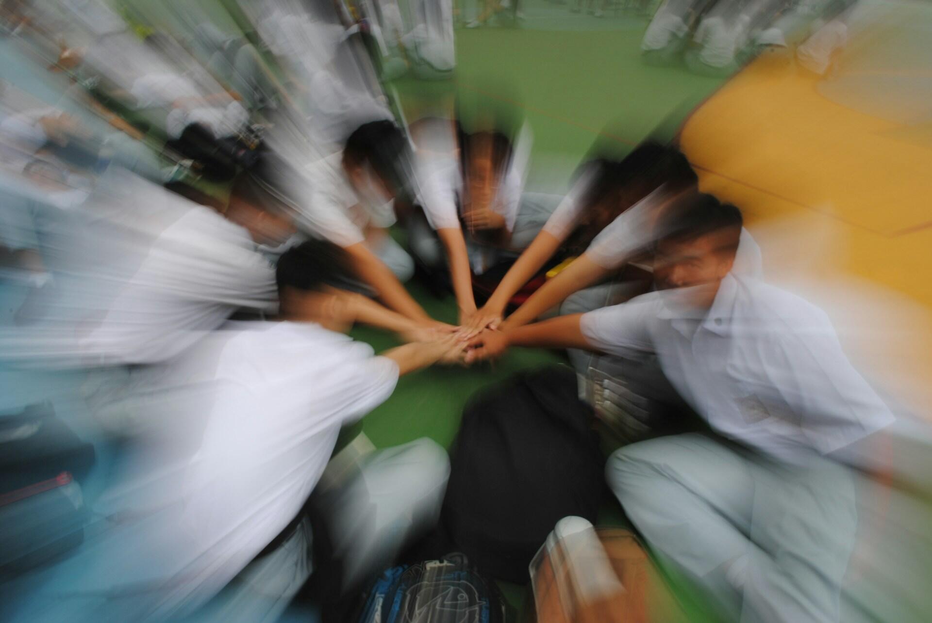 Mężczyźni składający dłonie jedna na drugiej w okręgu.