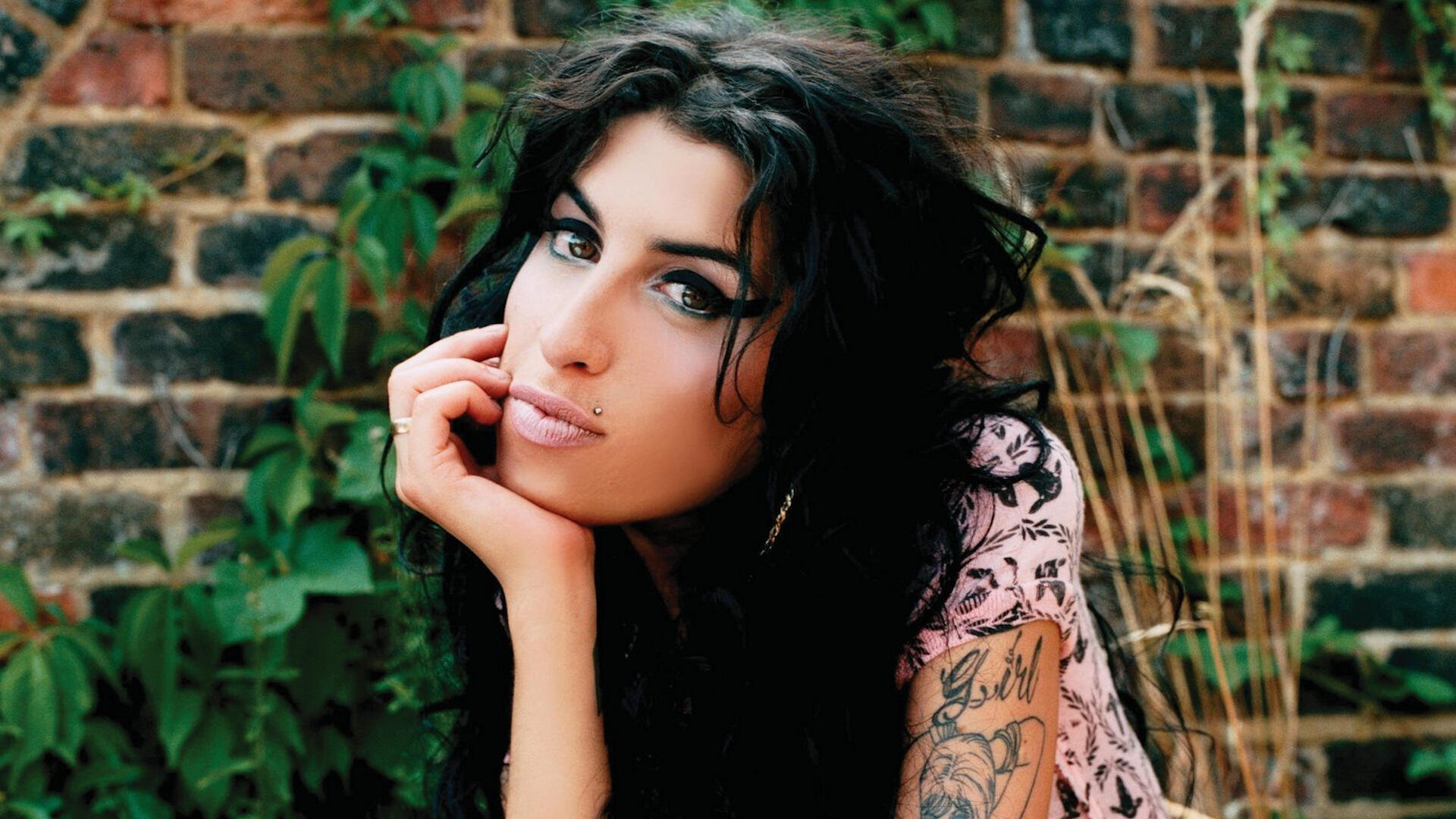 Amy WInehouse na tle murowanej ścianyAm