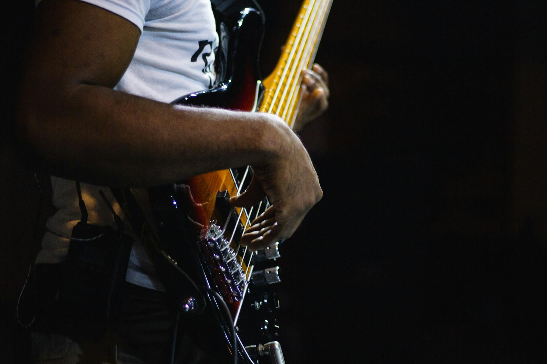 Mężczyzna grający na gitarze basowej na scenie.