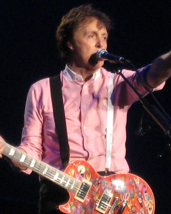 Paul McCartney na scenie z gitarą.