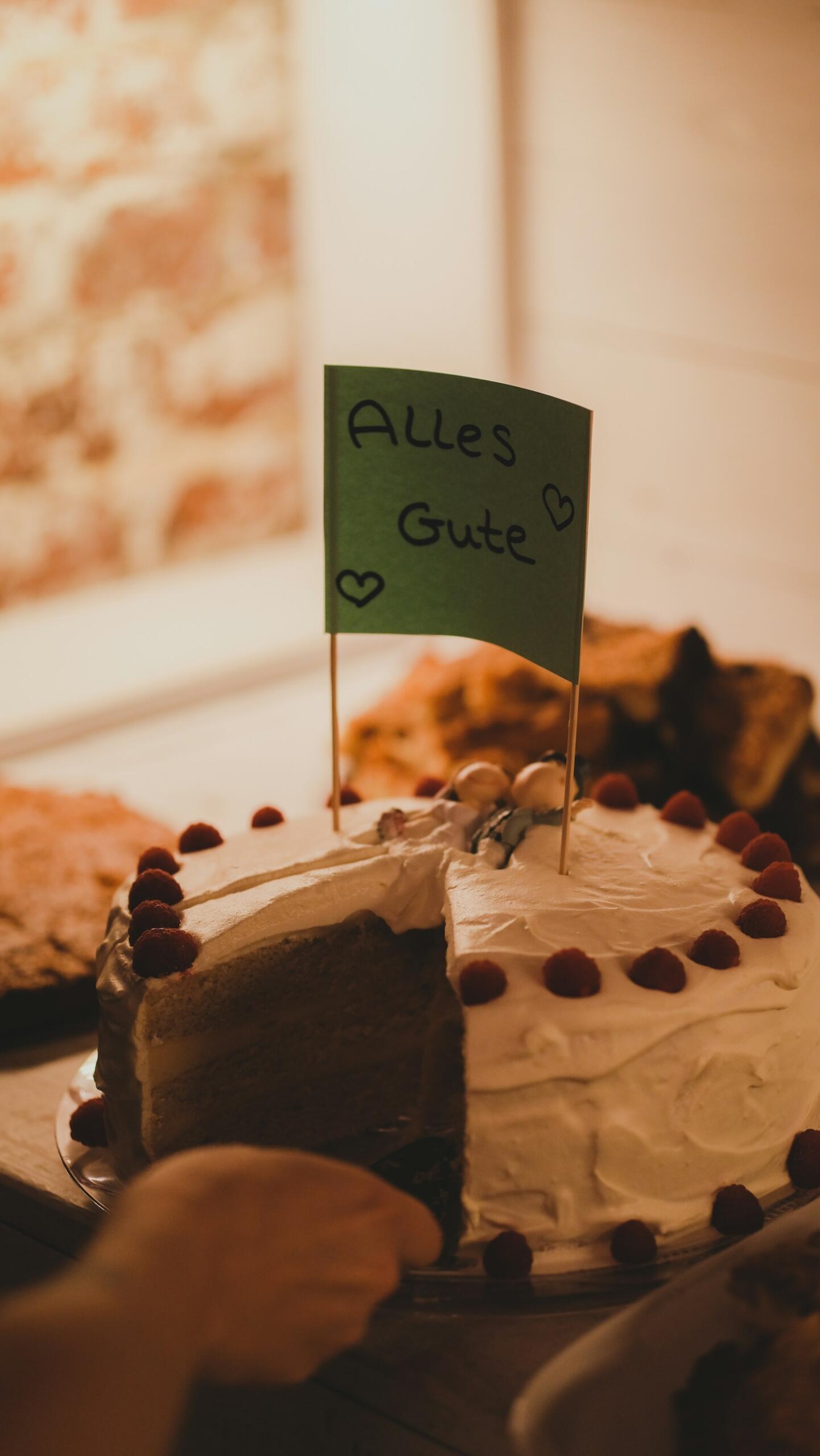 Tort s wykrojonym kawałkiem i napisem „alles gute”.
