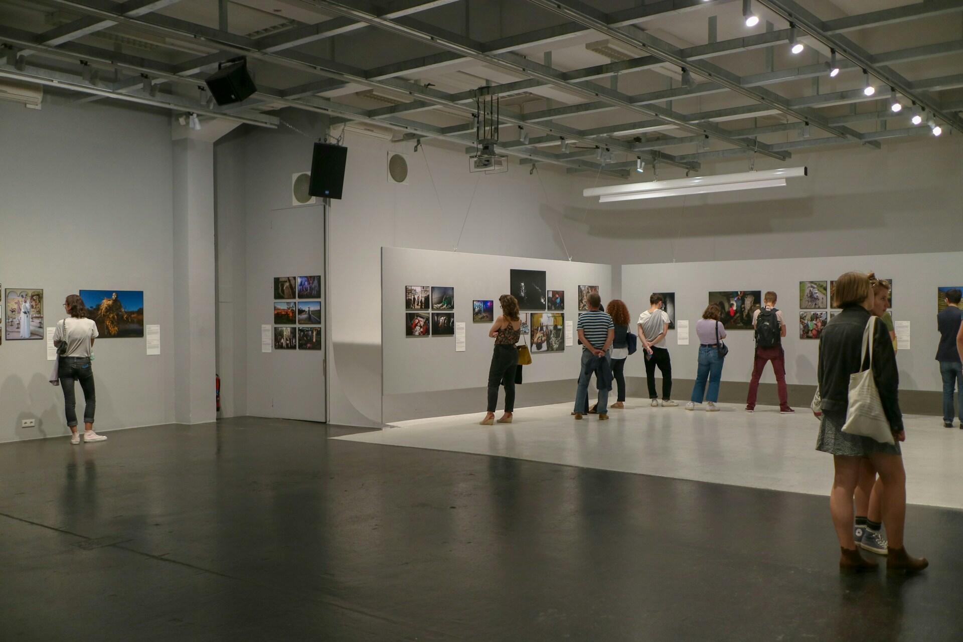 Kilkanaście osób paceruje po sali w galerii sztuki lub muzeum i ogląda zaprezentowane prace. Unsplash: yeonhee