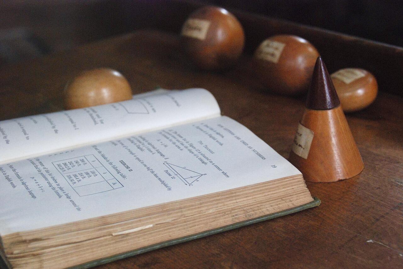 Drewniany stożek obok książki do matematyki