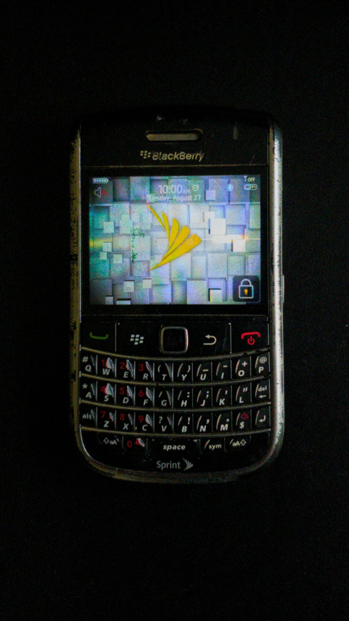 Telefon Blackberry z kolorową tapetą, na czarnym tle