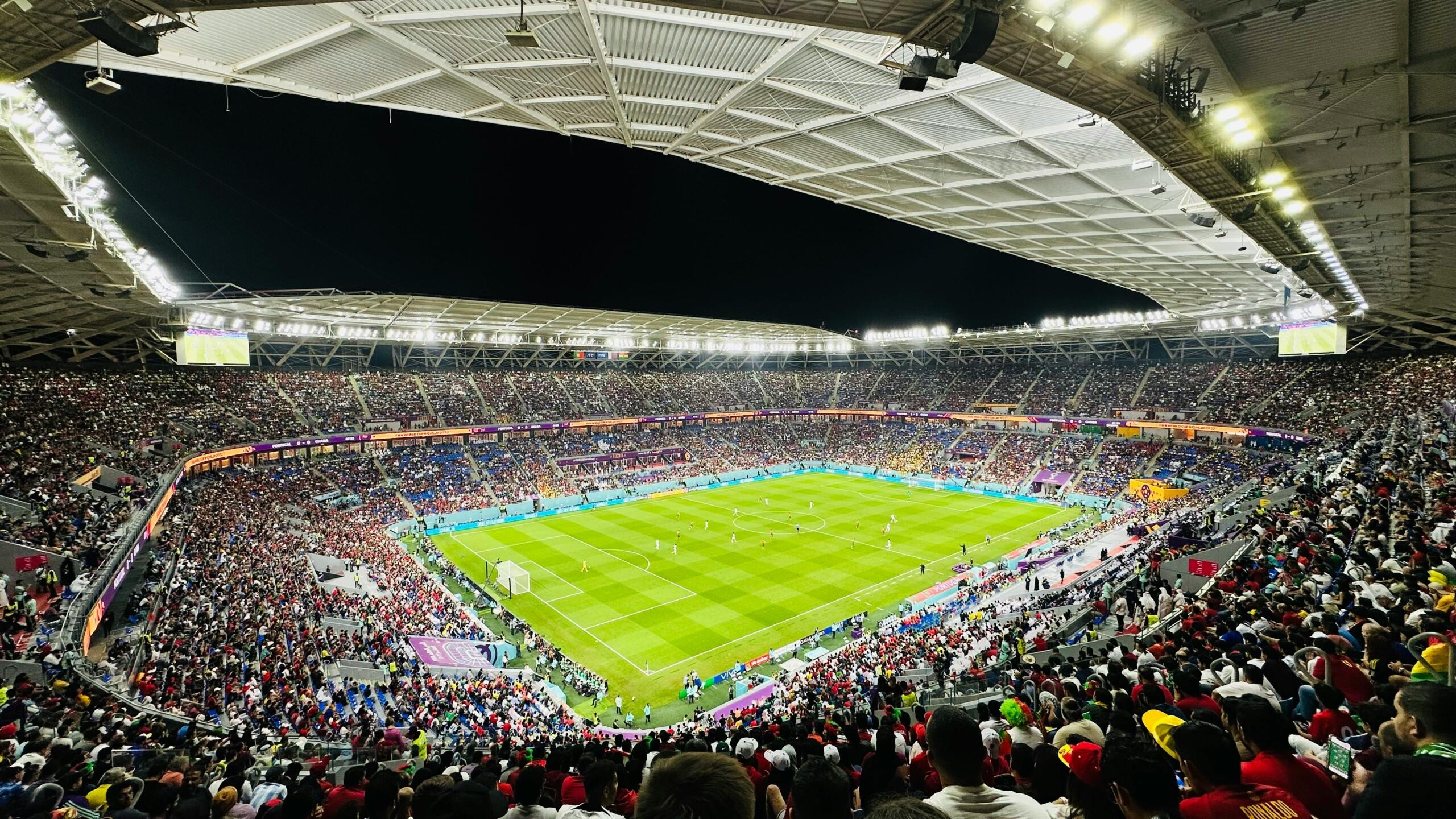 Kibice oglądający mecz piłki nożnej na wypełnionym stadionie podczas wieczornego turnieju