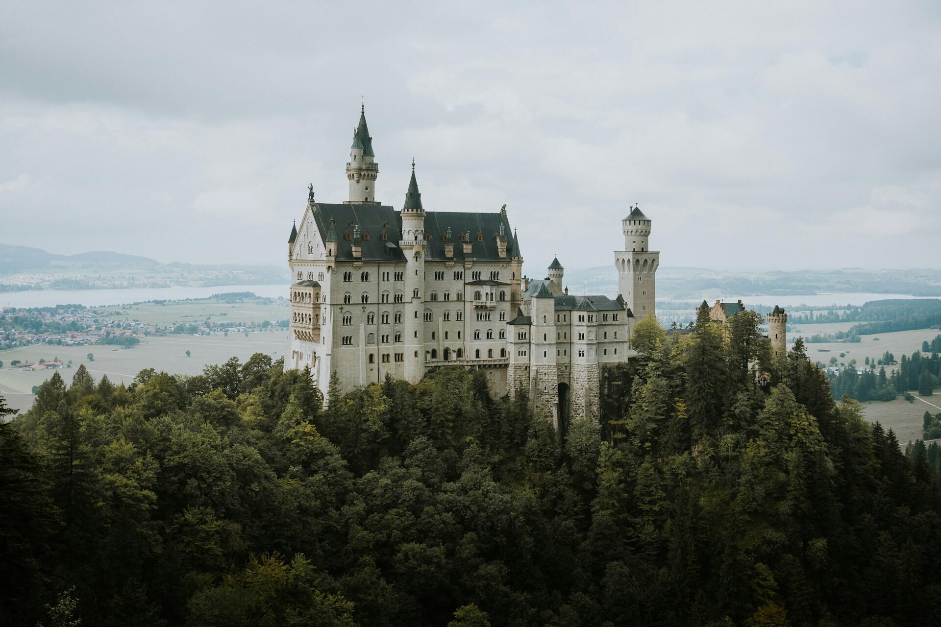 Zamek Neuschwanstein w Niemczech, malowniczo ulokowany na porośniętej lasem górze