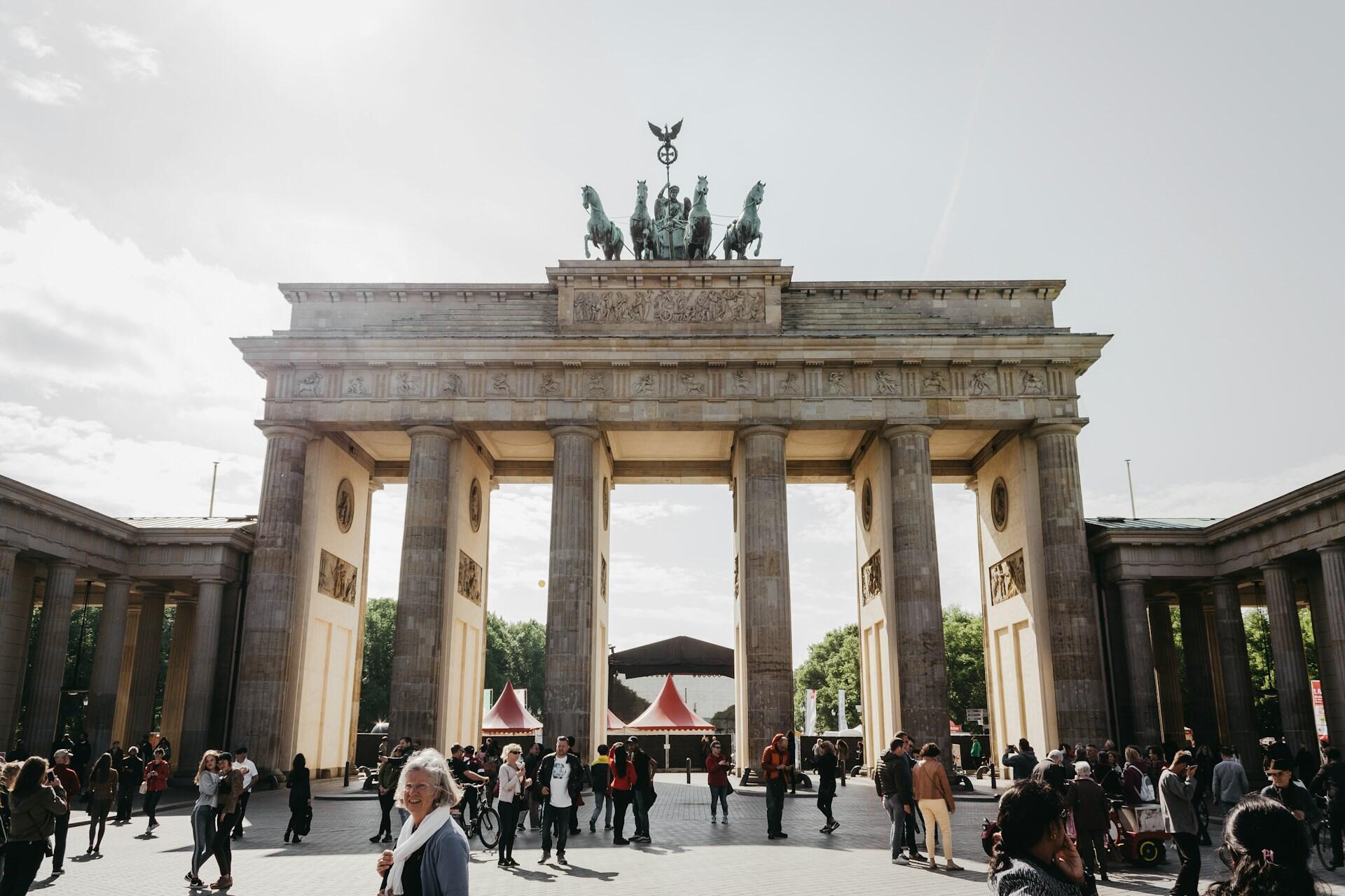 Ludzie zgromadzeni wokół Bramy Brandenburskiej w Berlinie. Unsplash: Marius Serban