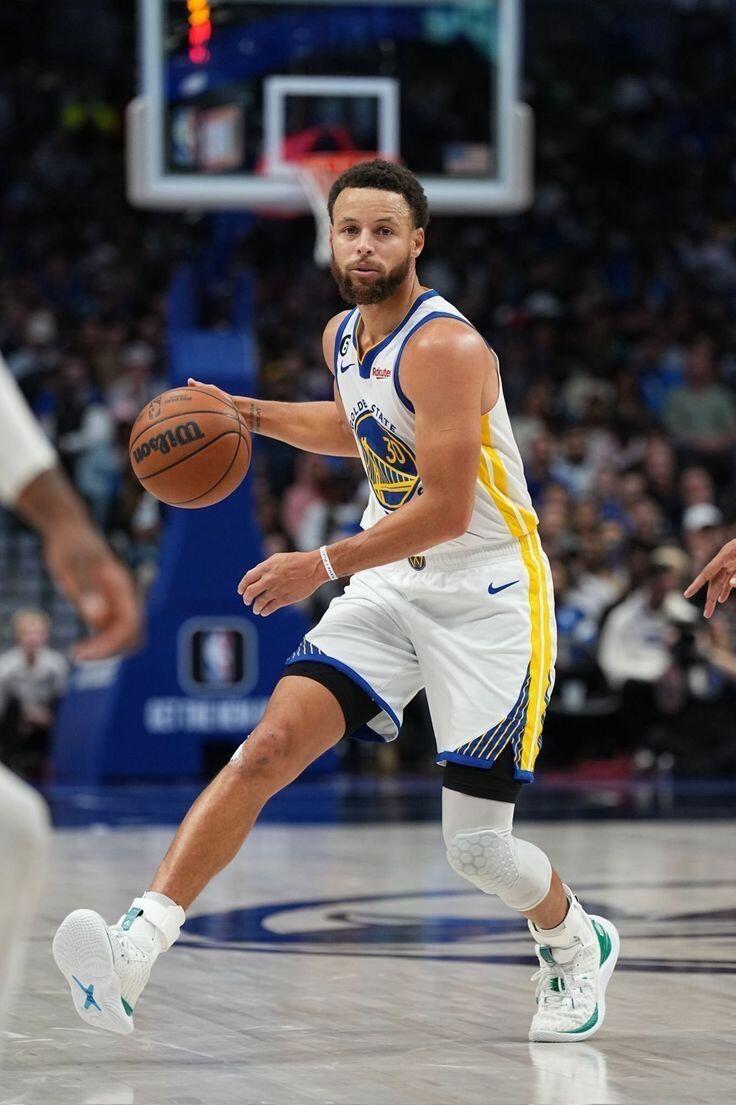 Koszykarz Stephen Curry kozłuje piłkę podczas meczu na boisku NBA.