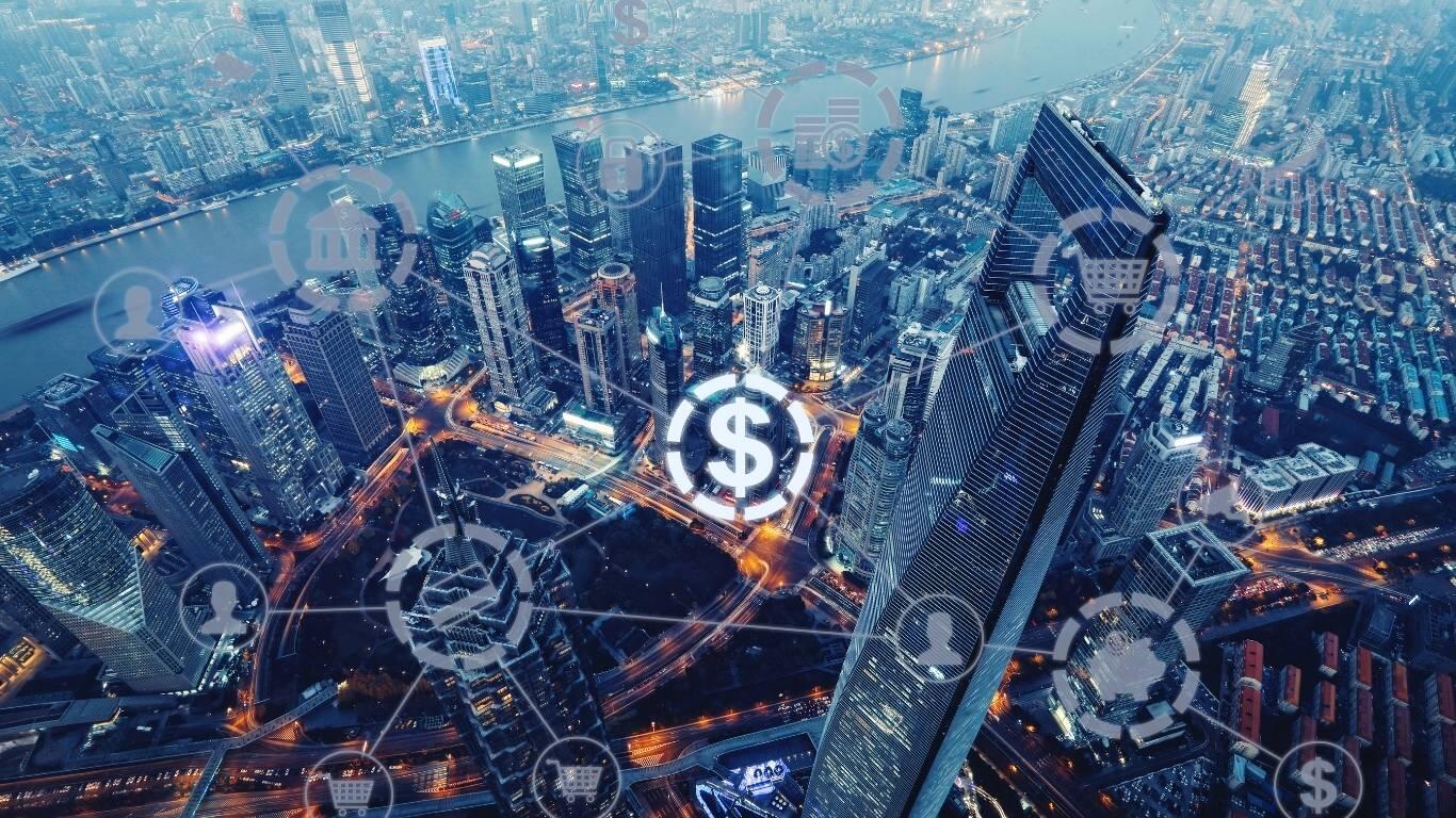 Widok z lotu ptaka na panoramę miasta o zmierzchu, z ikonami symbolizującymi finanse i łączność cyfrową na tle drapaczy chmur.