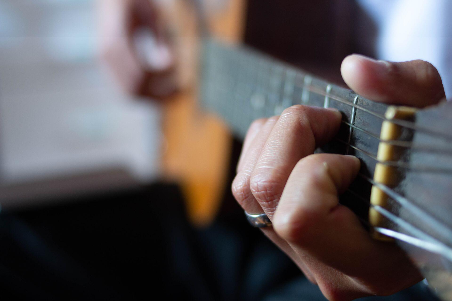 mãos de pessoa a tocar guitarra