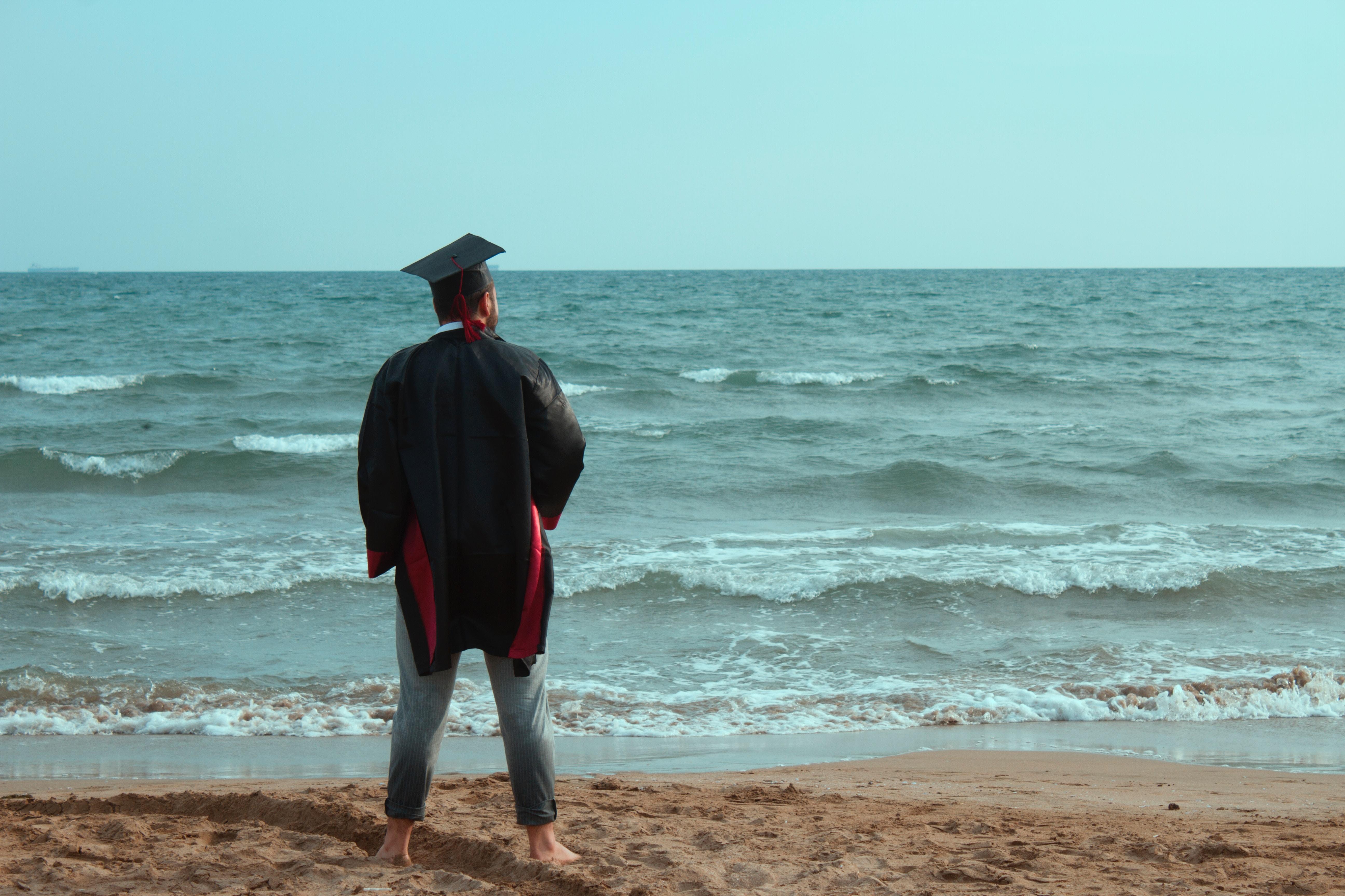 Estudante, na praia, a observar o mar.