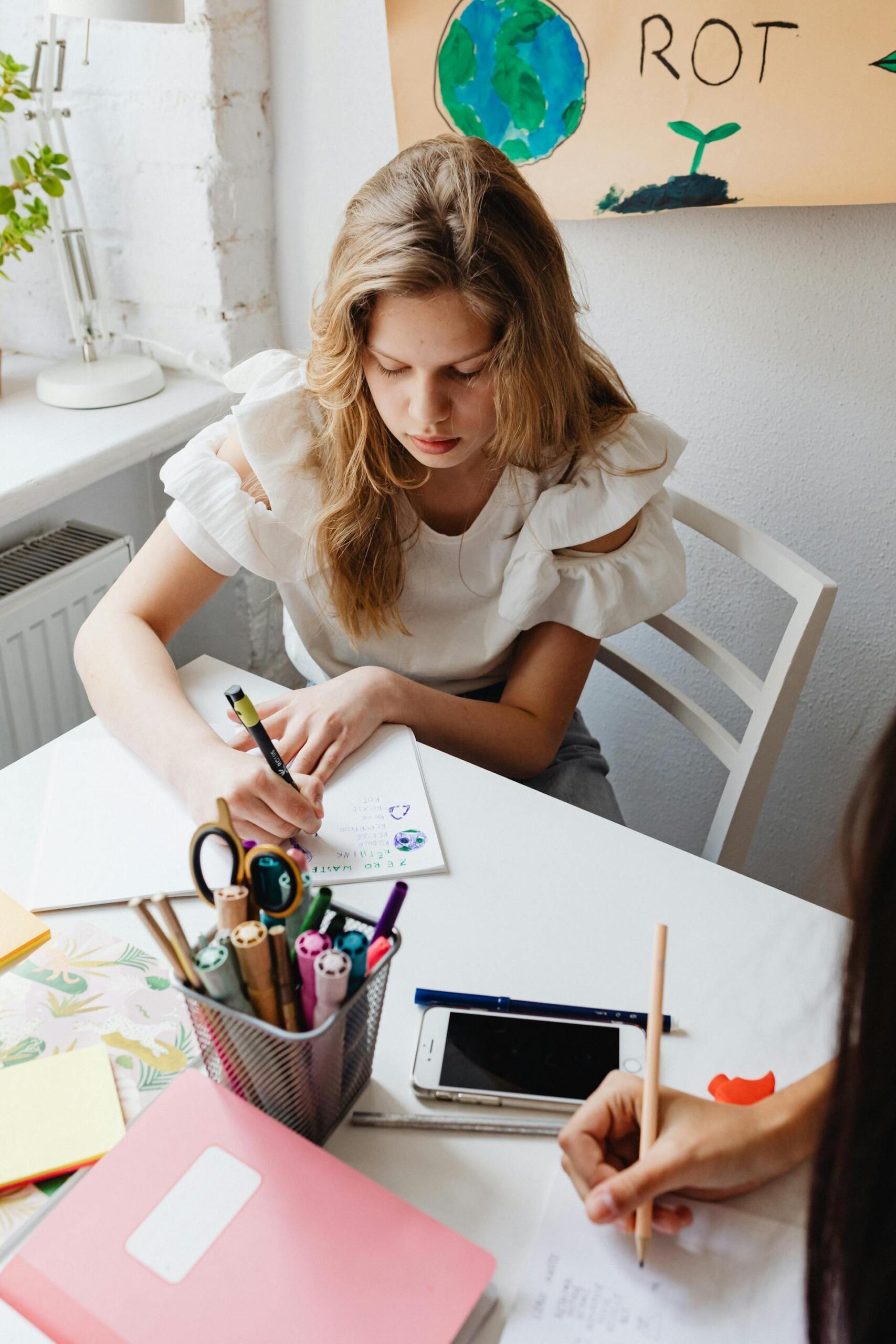 alunas a escrever em folhas em cima de secretária