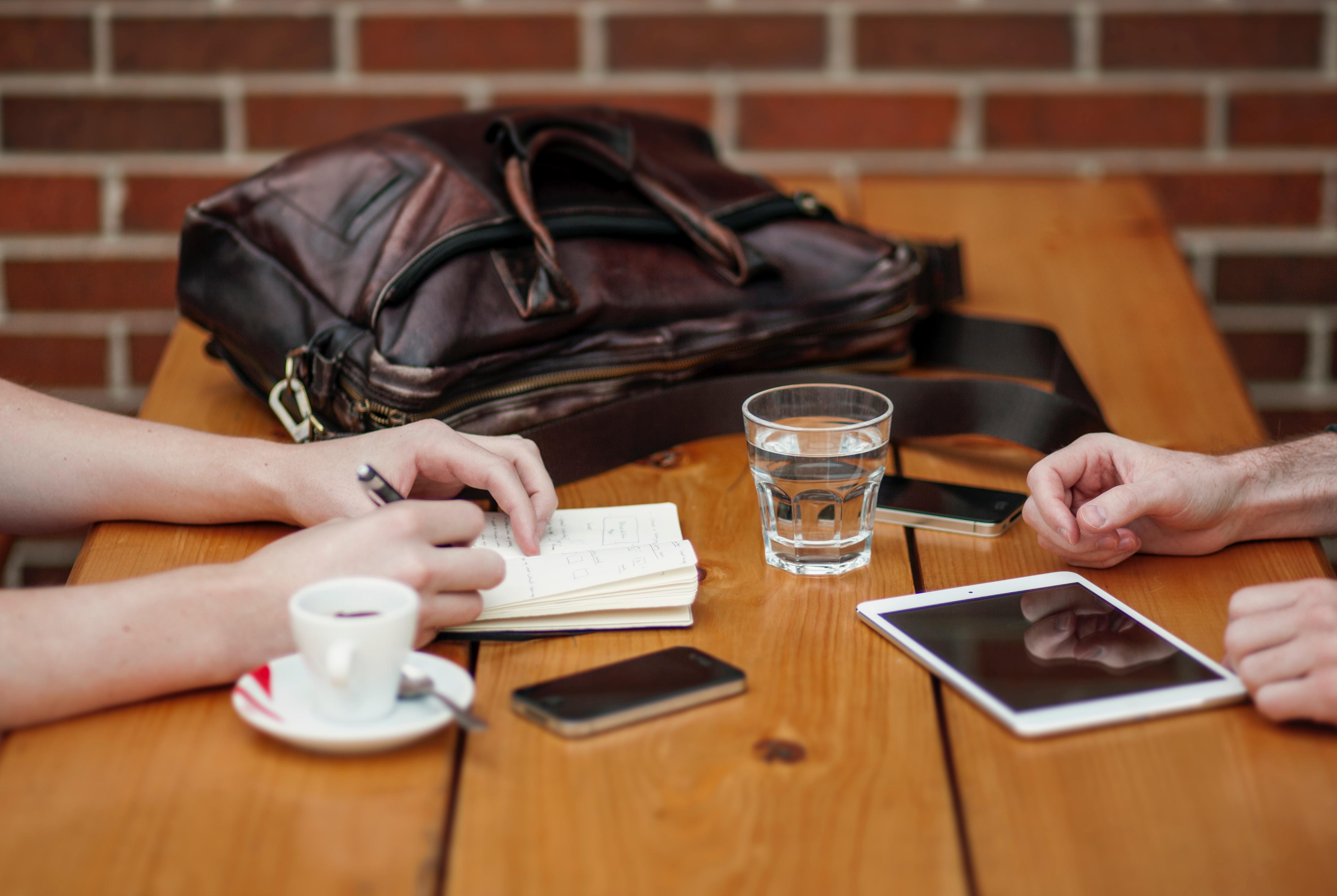 Uma mesa, dois estudantes, um smartphone e um tablet.