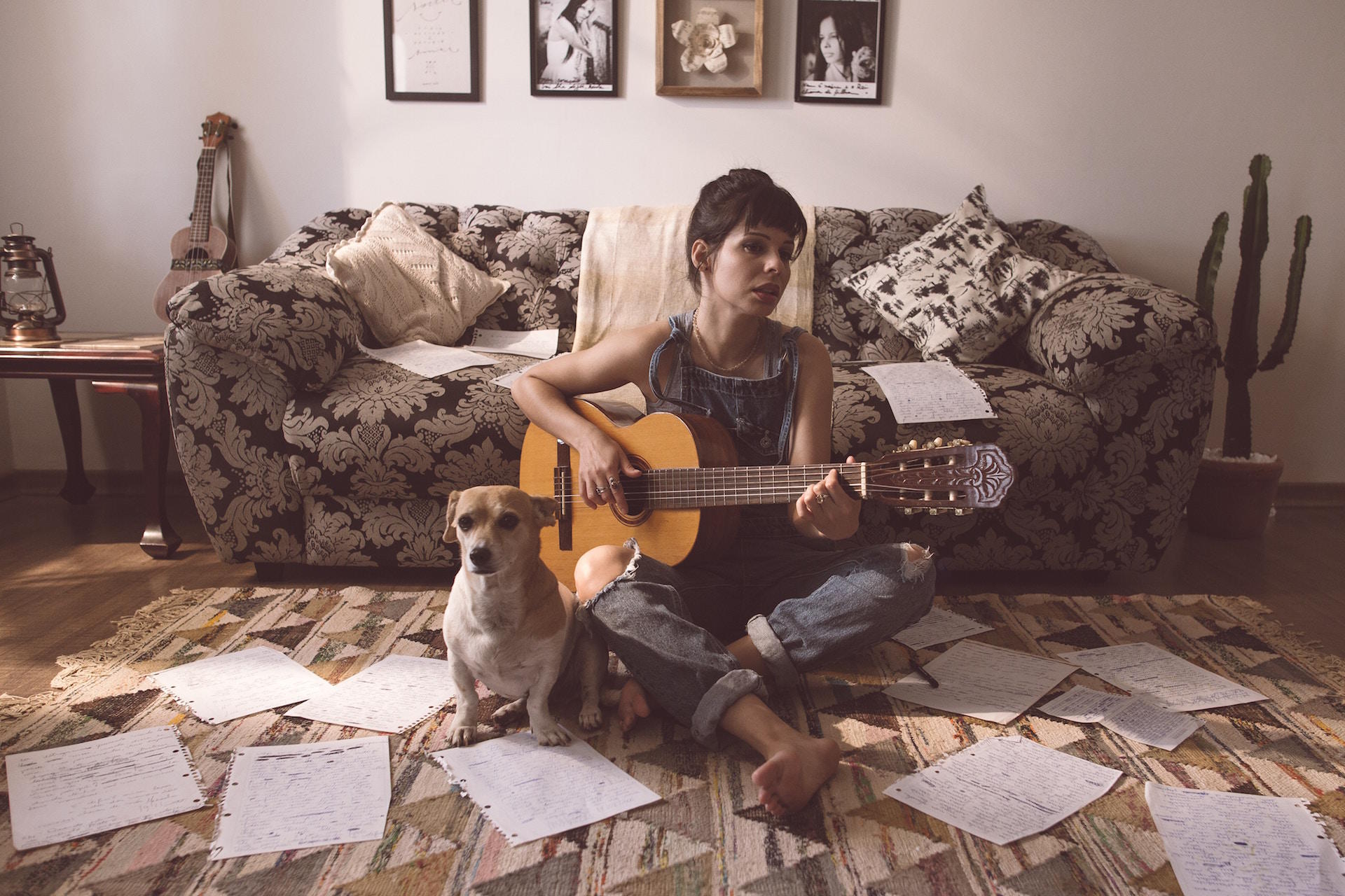 Aluna de guitarra a praticar em casa na companhia do seu cão