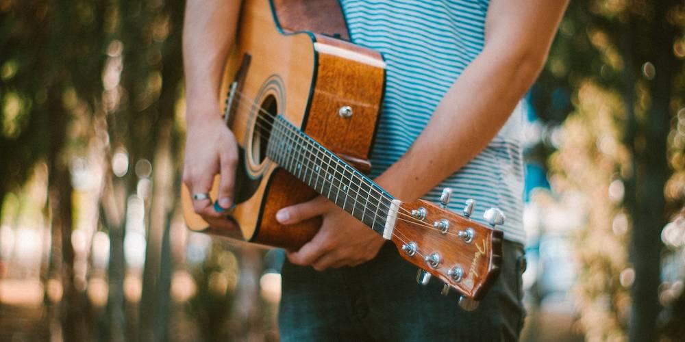 Guitarrista segura a viola e uma palheta no exterior.