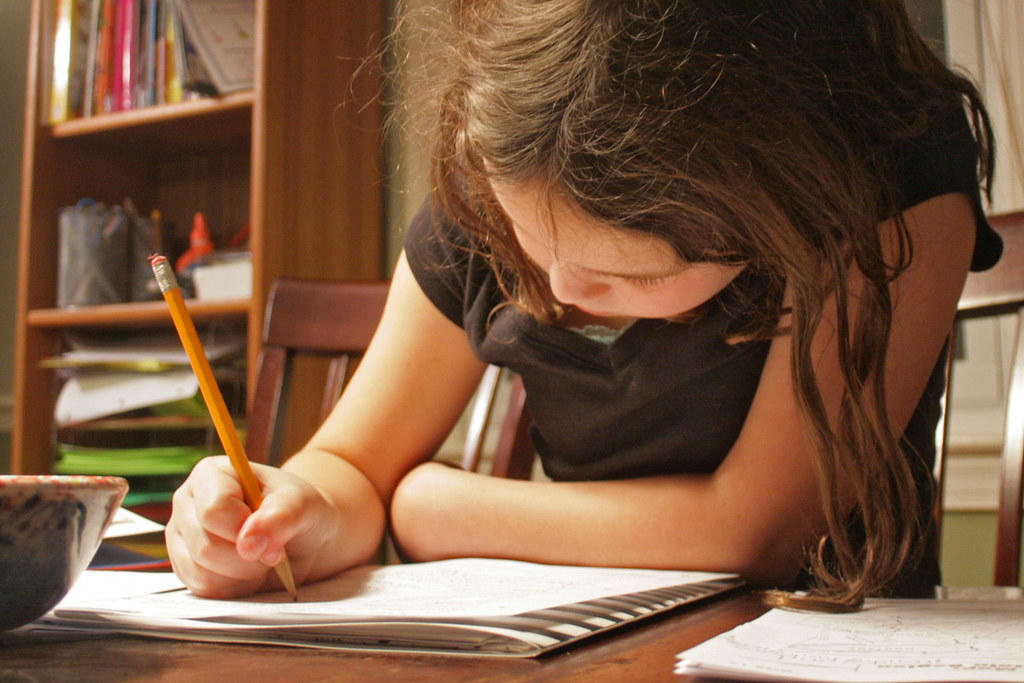 Menina com um lápis e um caderno, a estudar matemática.