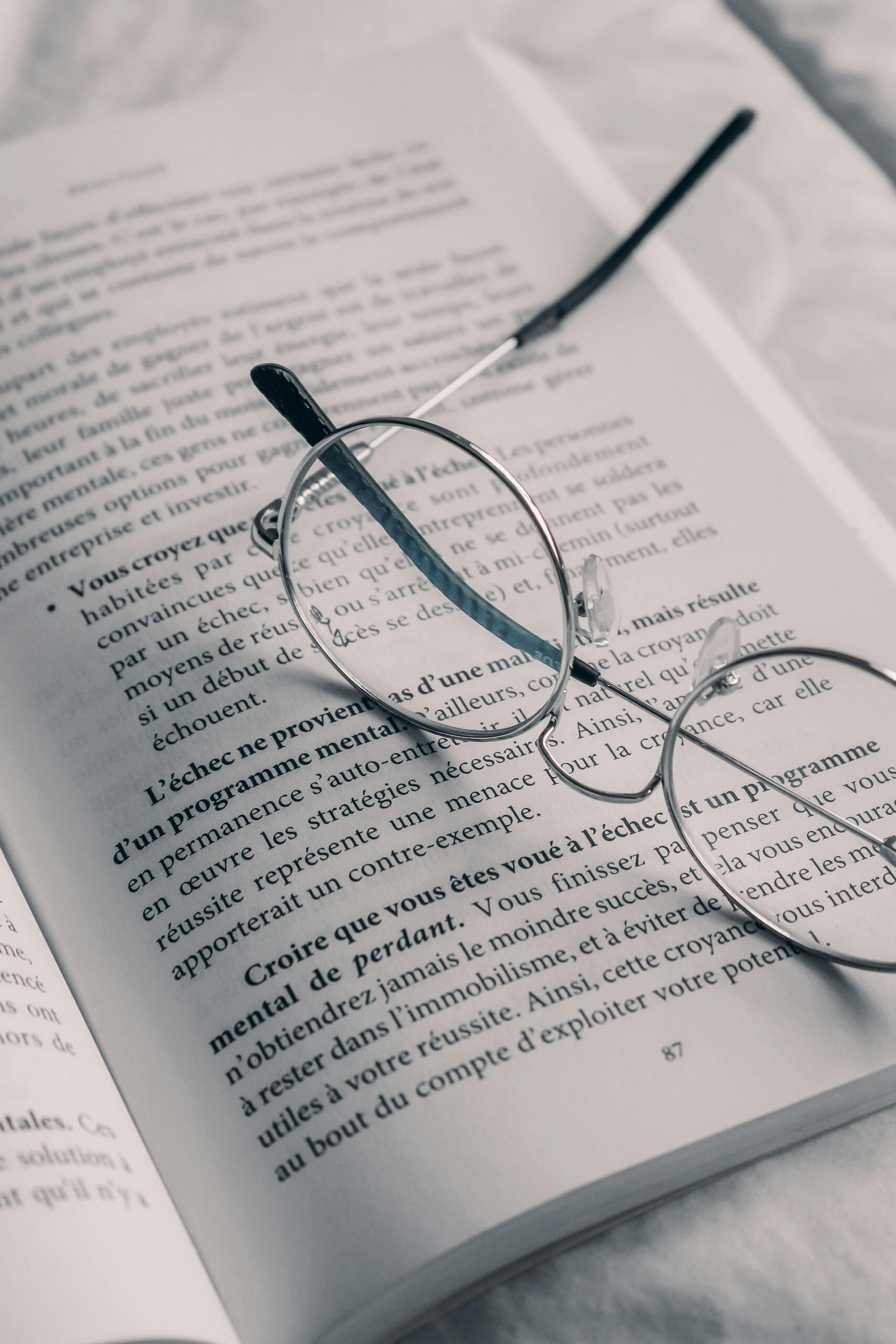óculos pousados em cima de um livro aberto
