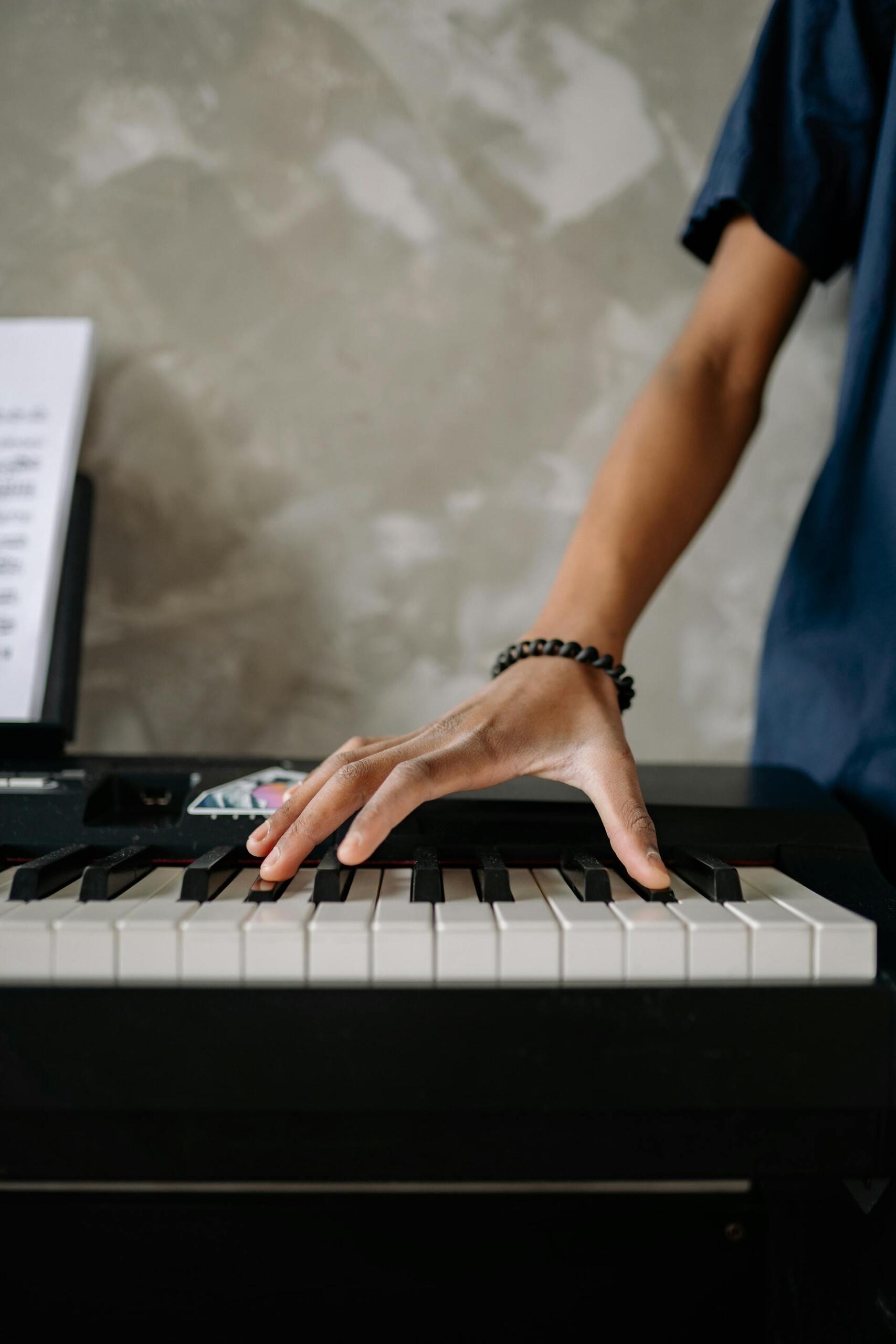 mão de pessoa a tocar em duas teclas de piano
