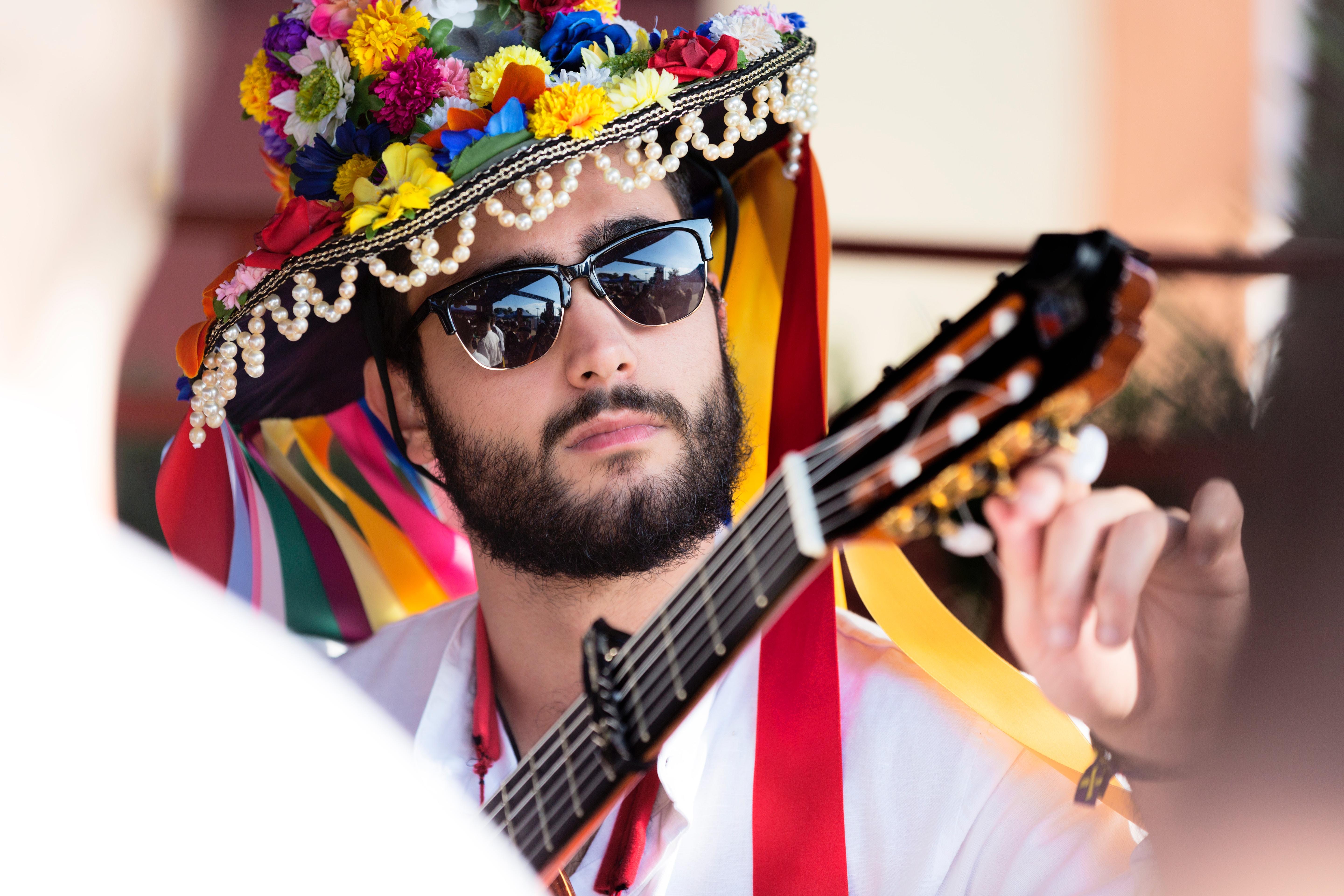 Um rapaz com um chapéu de flores a afinar uma guitarra.
