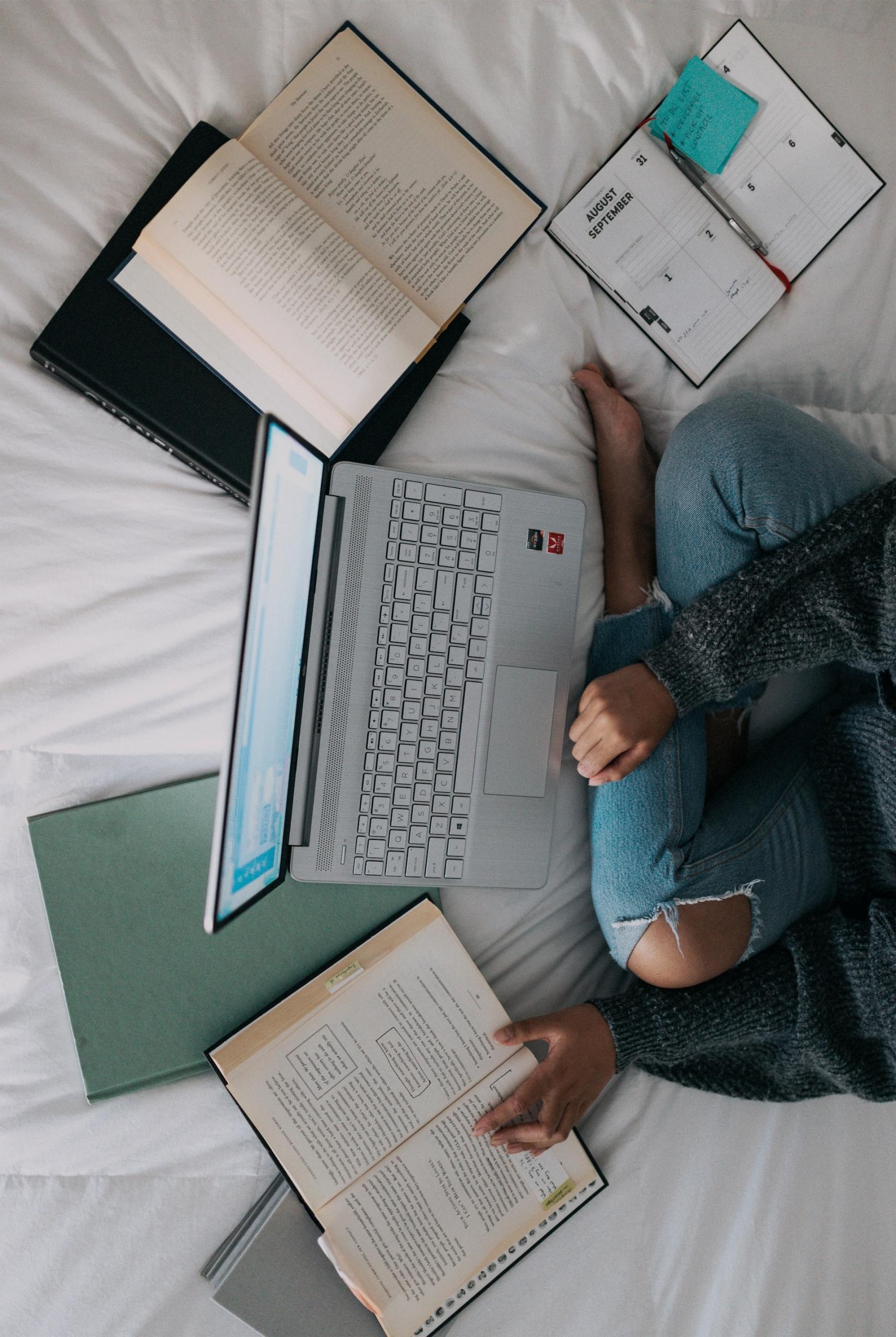 mulher com livros e computador portatil