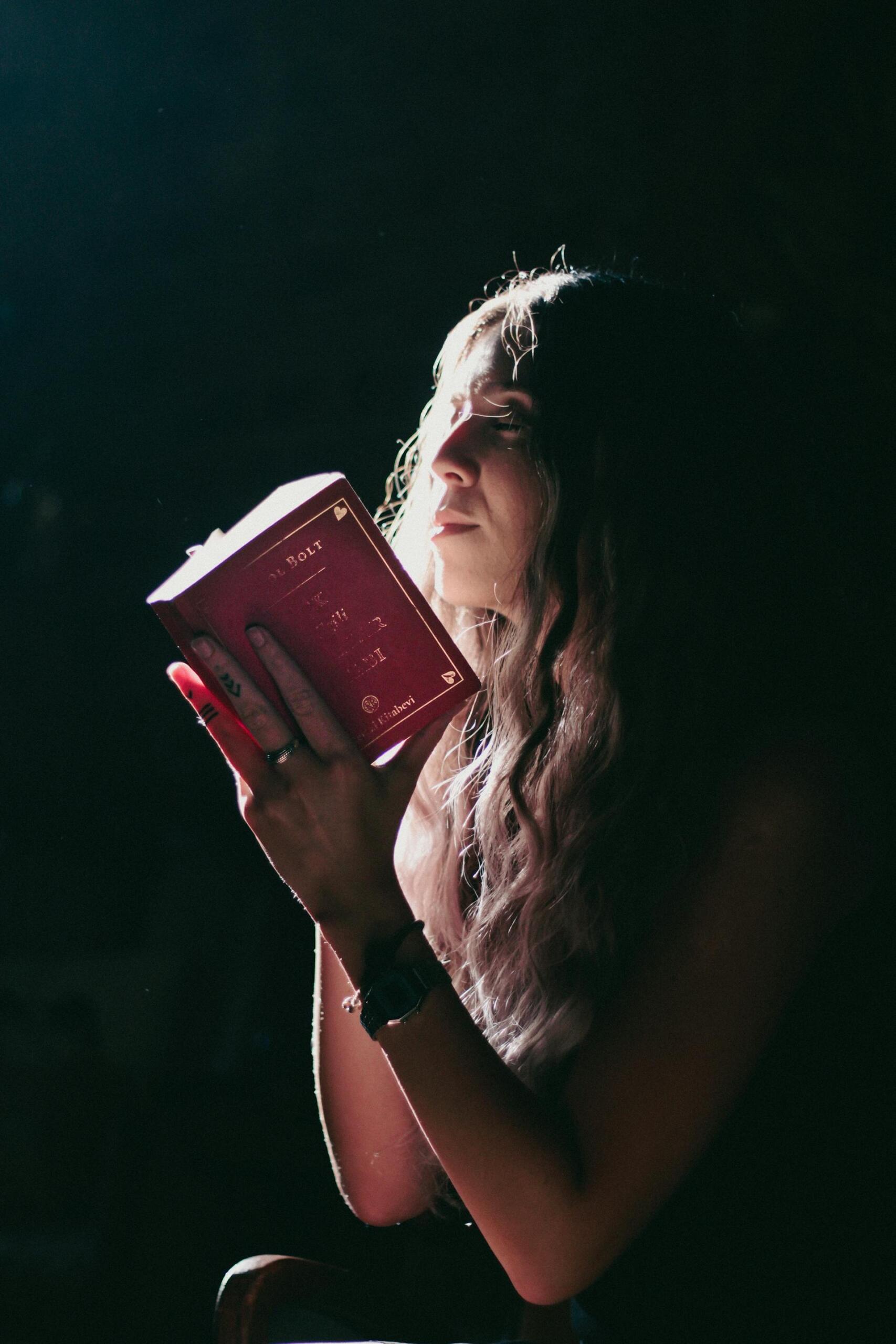 mulher de olhos fechados com livro aberto à frente da cara