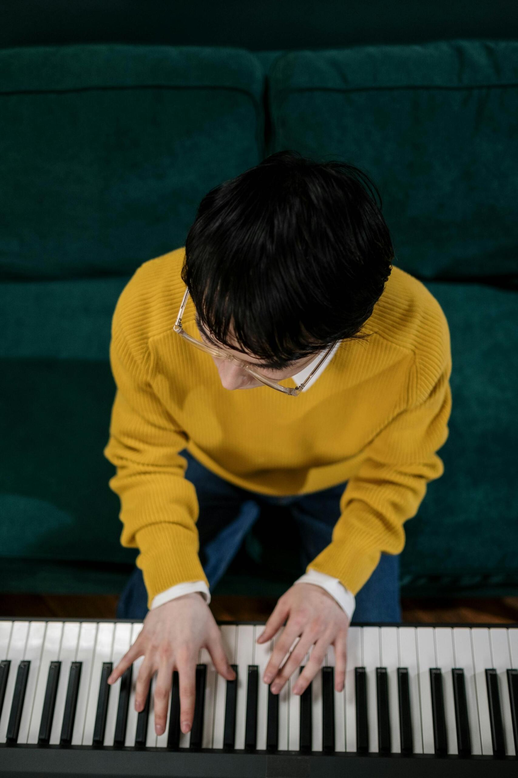 homem de camisola amarela a tocar piano