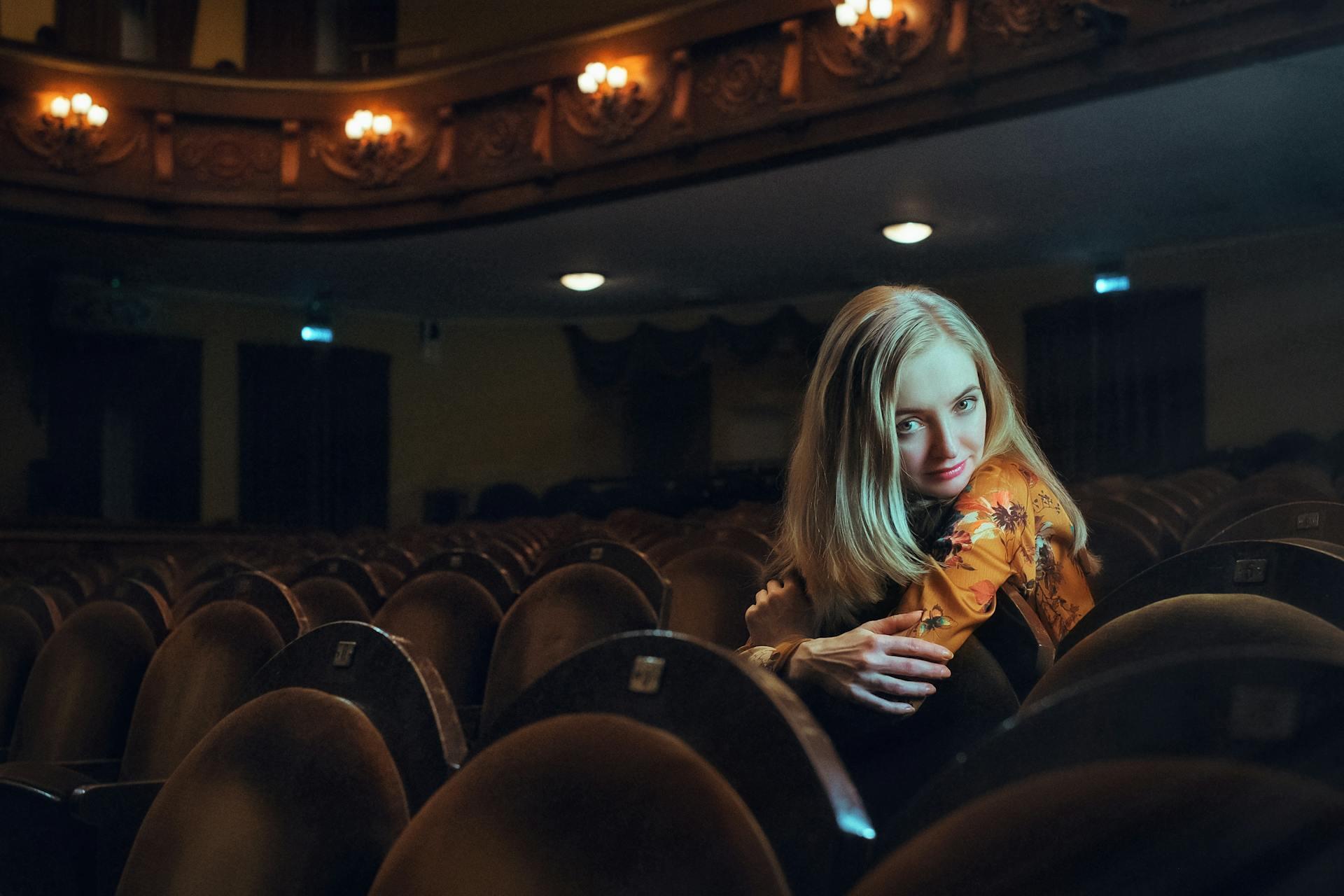mulher sentada no repouso de uma cadeira em sala de cinema