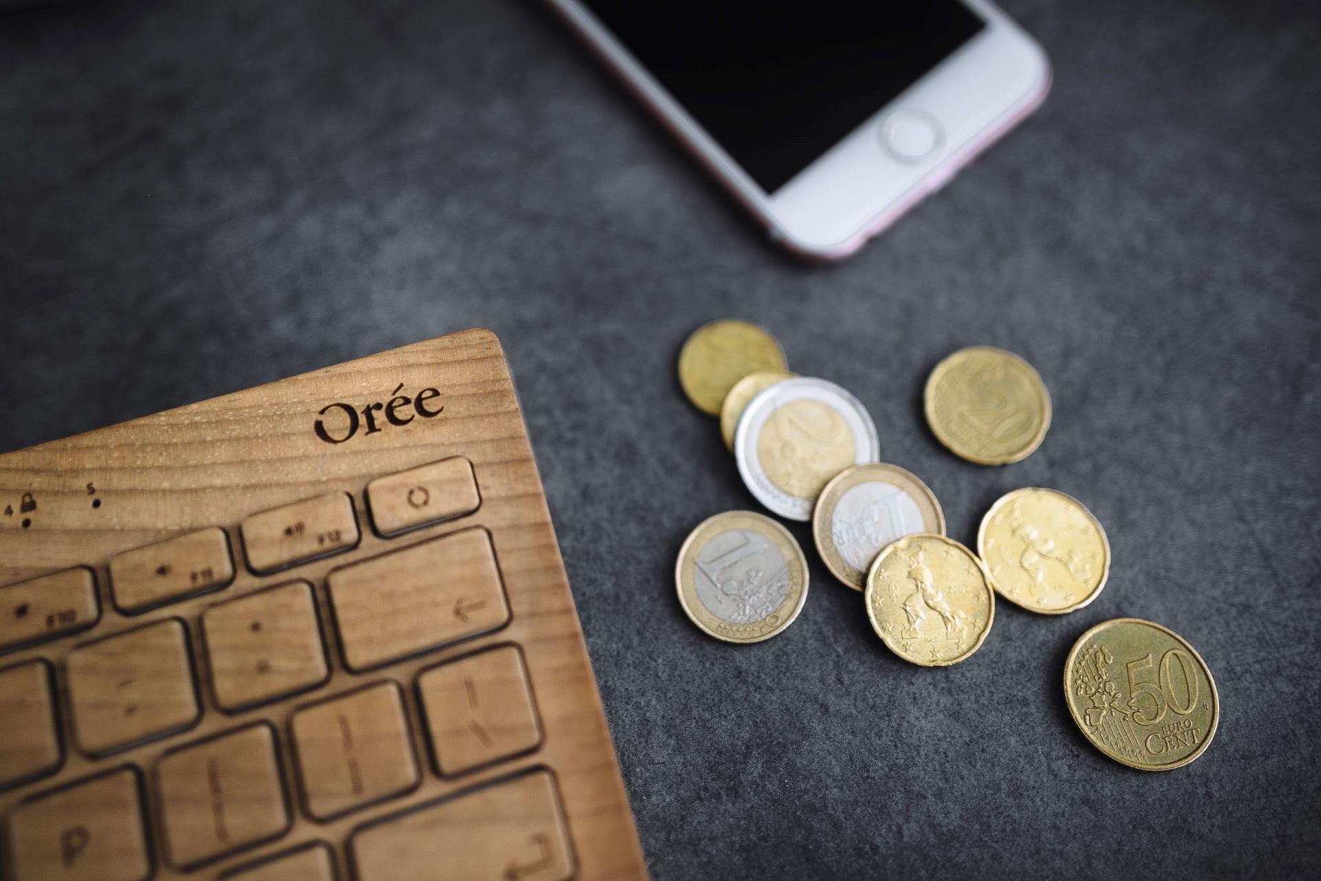 Teclado, smartphone e moedas