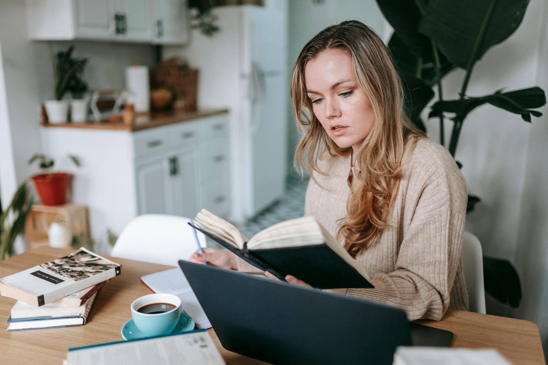 mulher a segurar livro com uma mão e a escrever com a outra