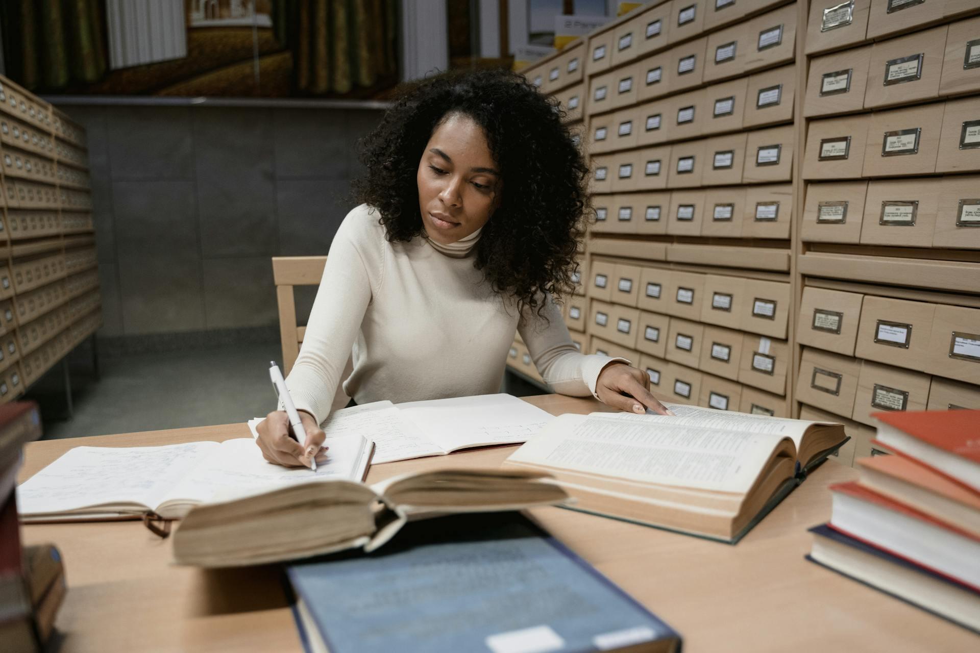 aluna em secretária com vários livros abertos