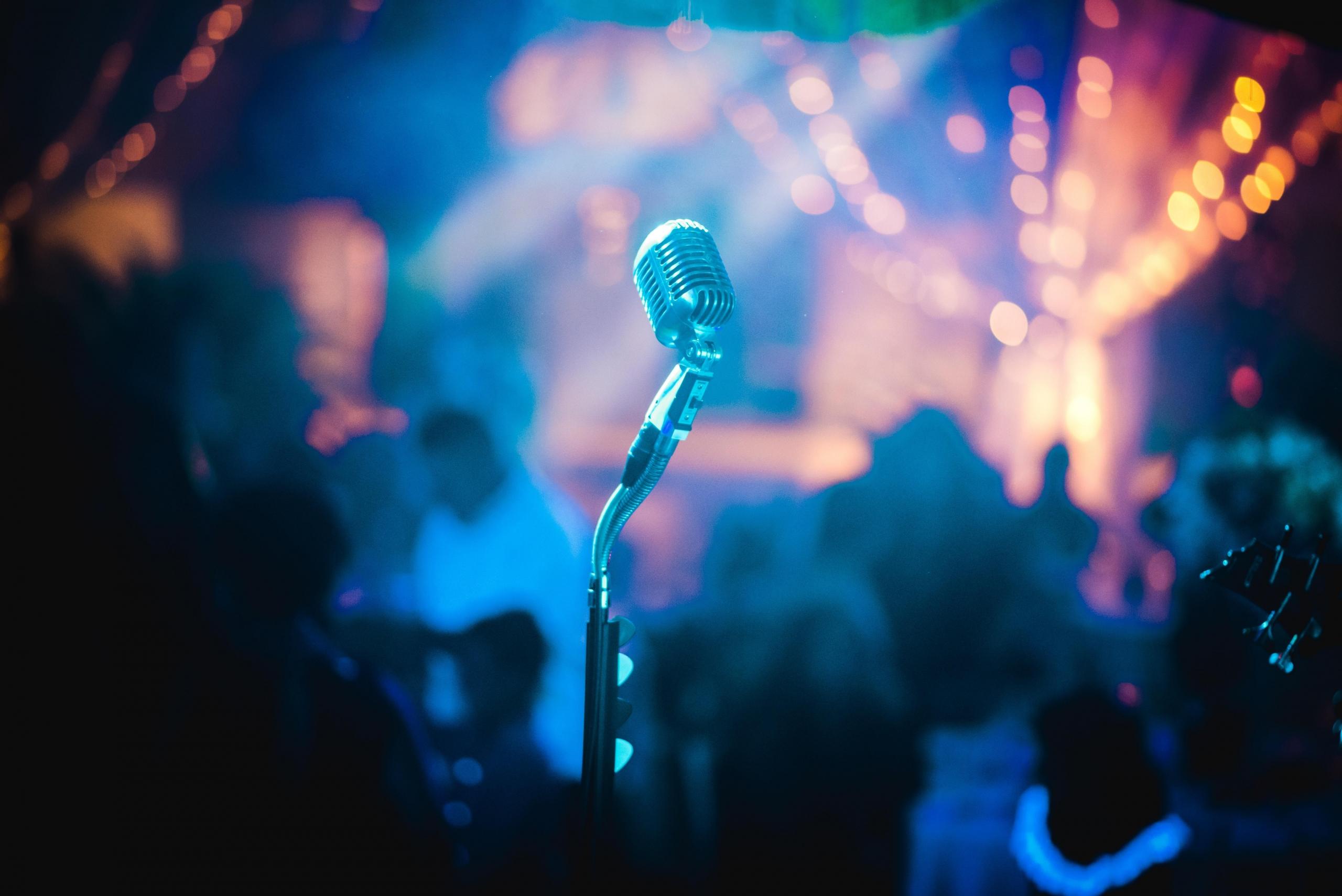 Um microfone, no palco de um bar iluminado com luzes coloridas.