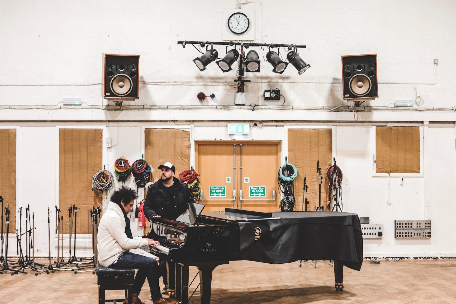 Professor e aluno de piano em aula numa sala ampla