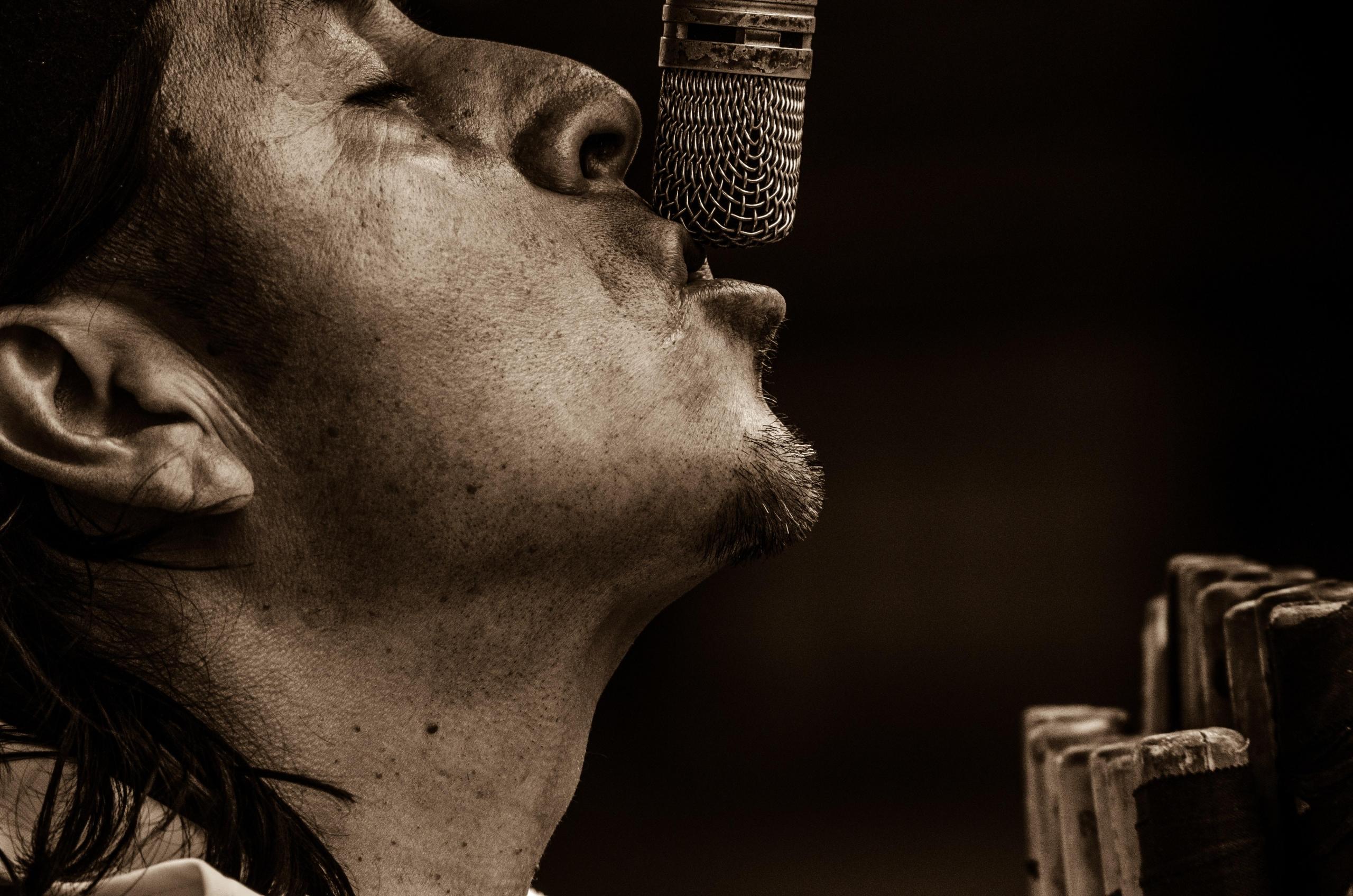 Um homem a cantar para um microfone.