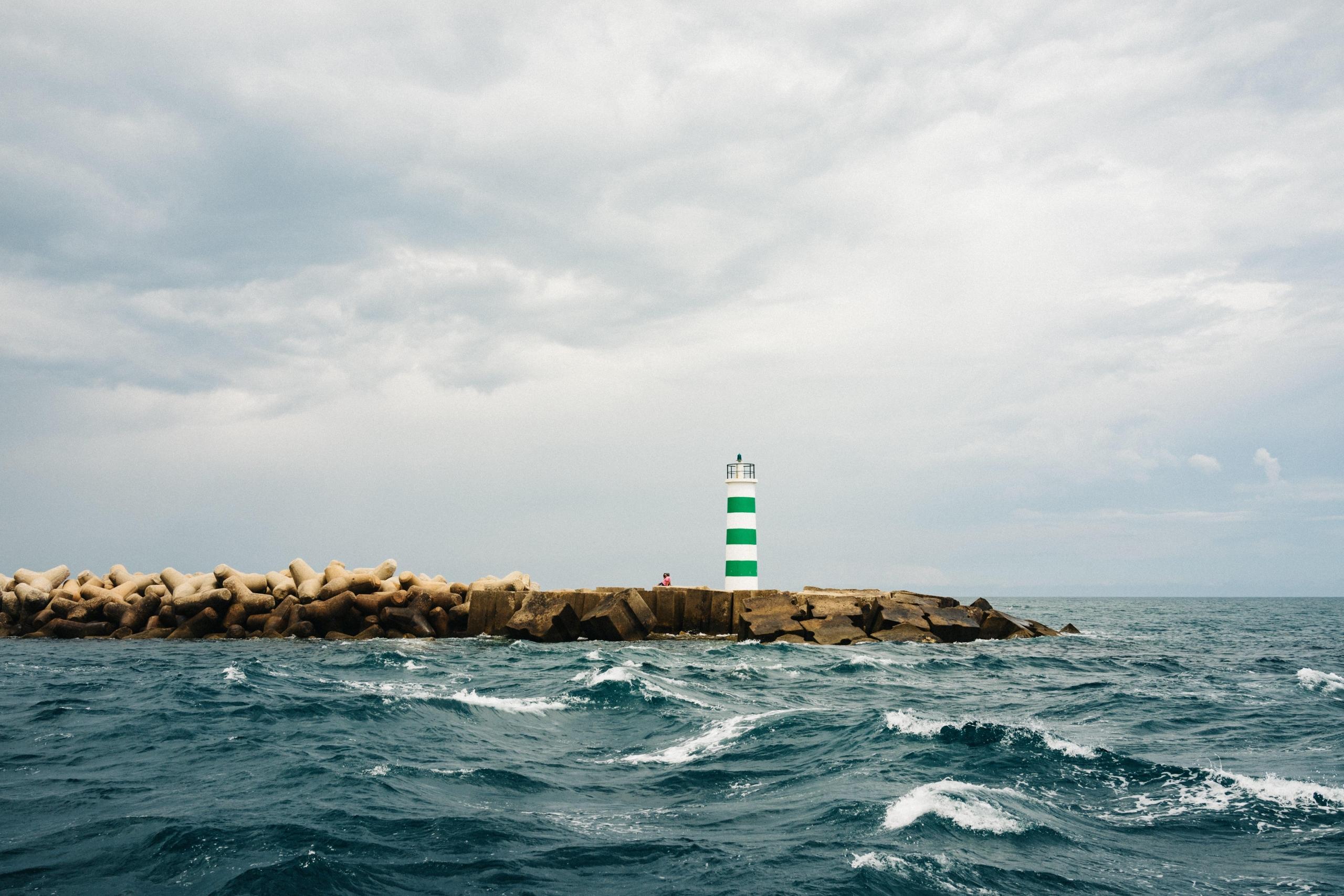 Uma fotografia do mar algarvio e de um pontão com um farol.