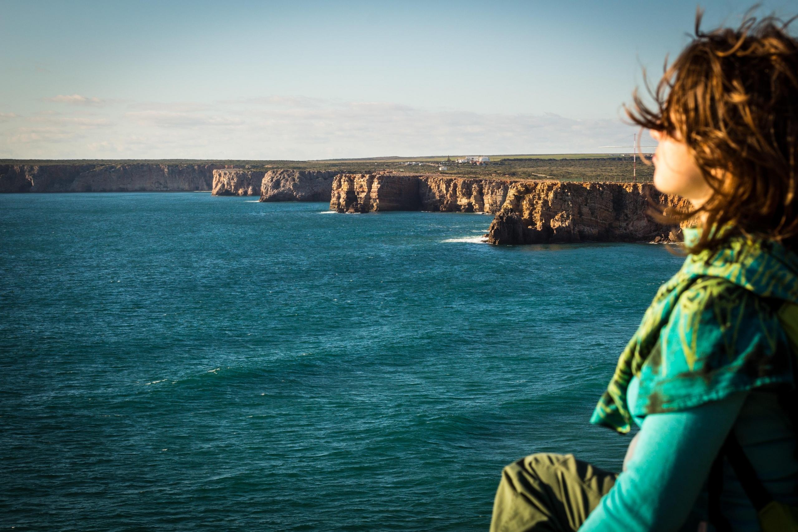 Alguém a meditar e fazer exercícios de respiração numa falésia do Algarve.
