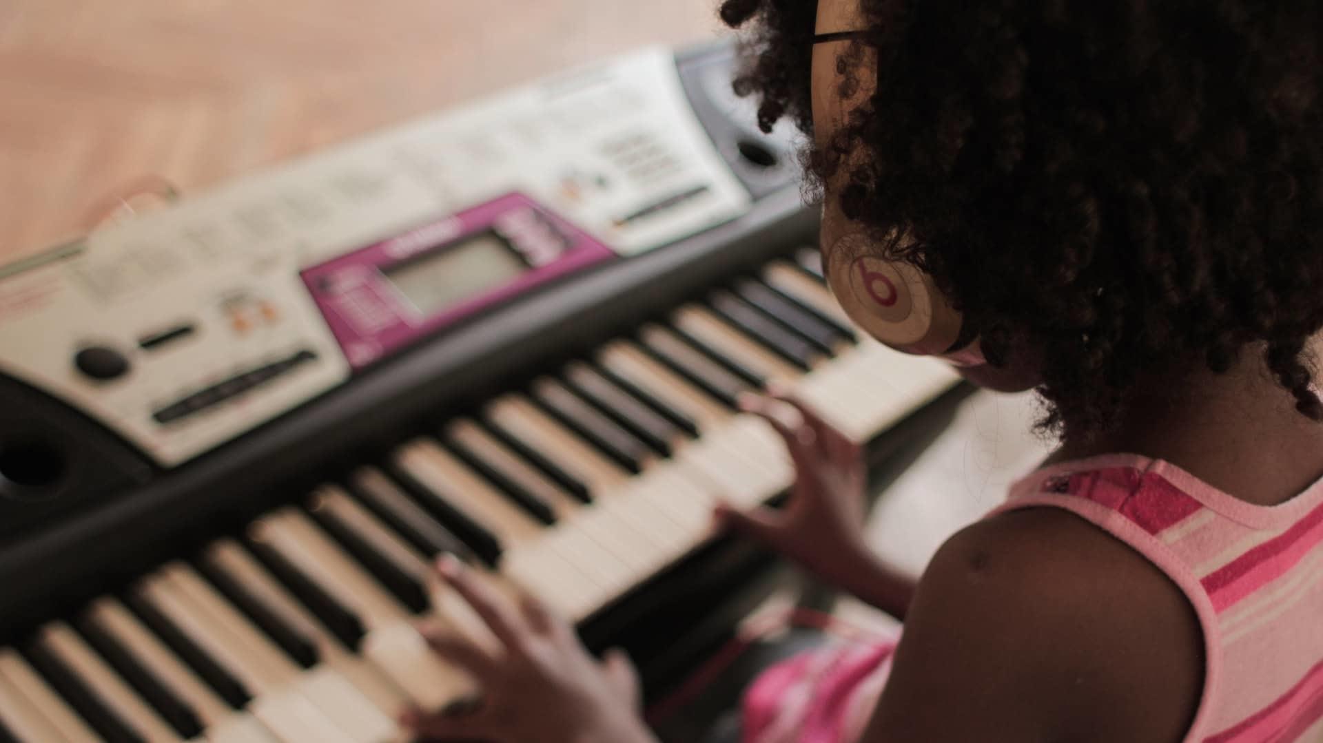 Menina treina piano em casa