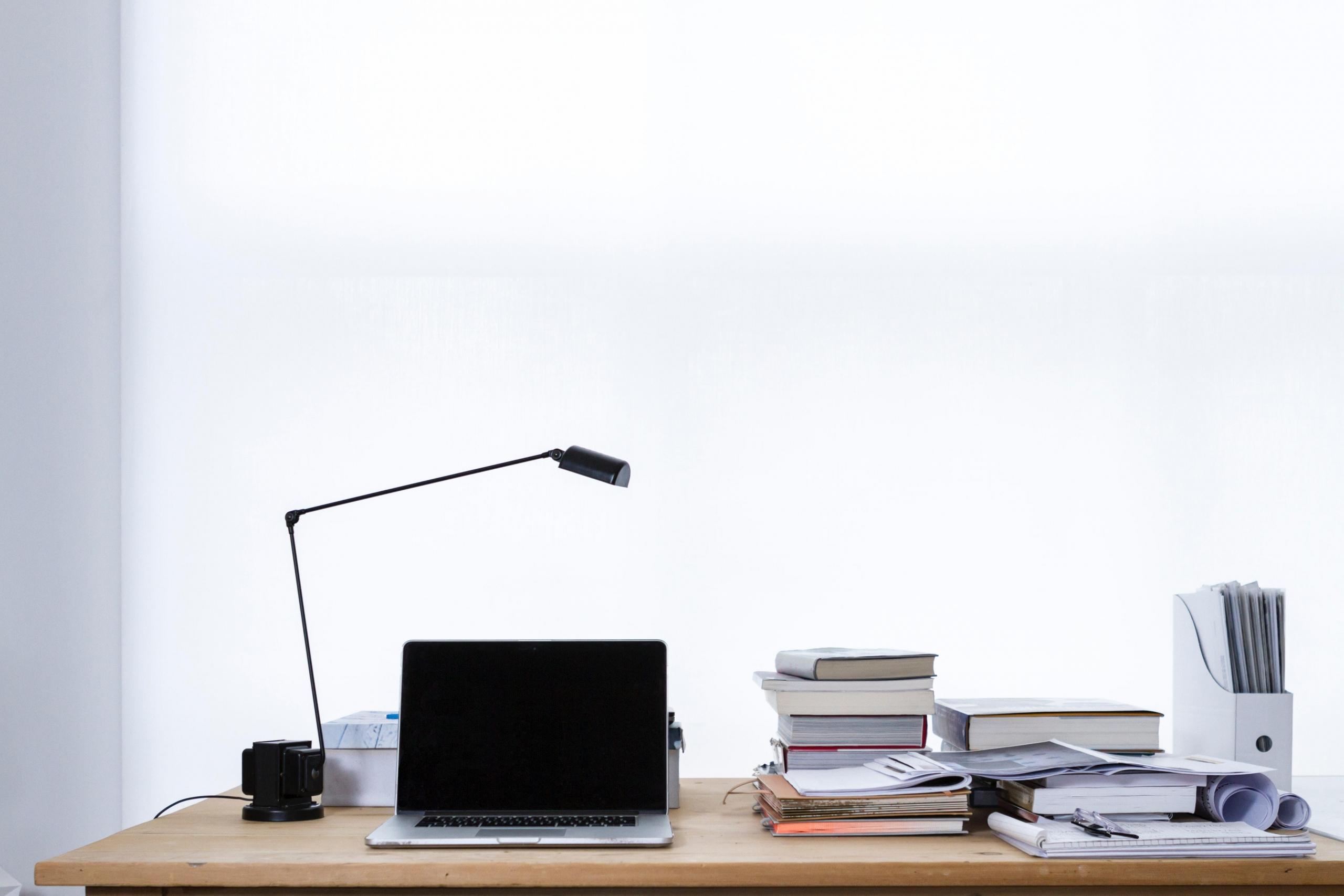 Secretária com livros, candeeiro e computador