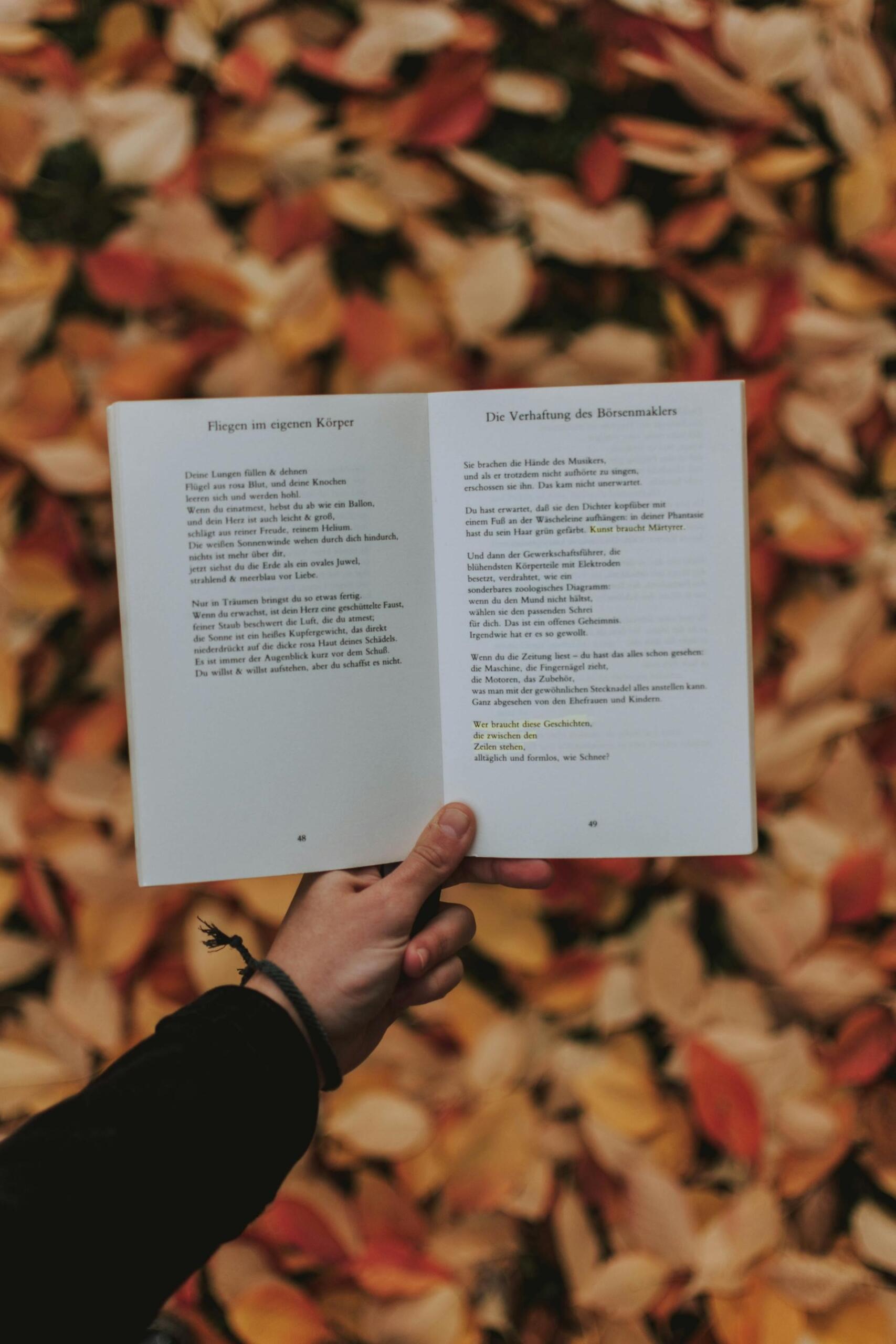 pessoa a segurar livro de poesia aberto com uma mão