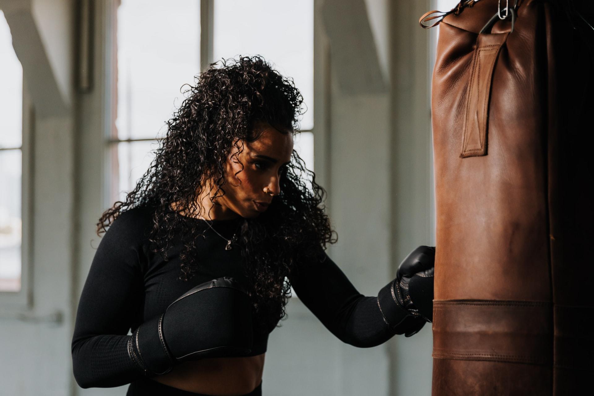mulher treinando boxe com luvas e um saco de luta