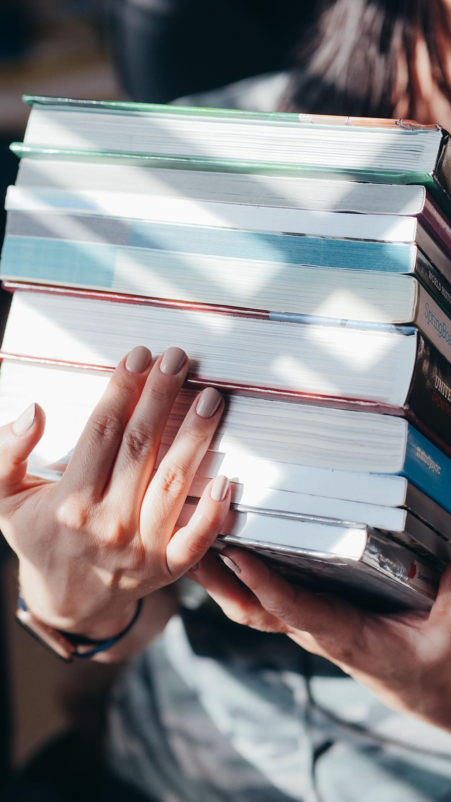 pilha de livros nas mãos de uma pessoa