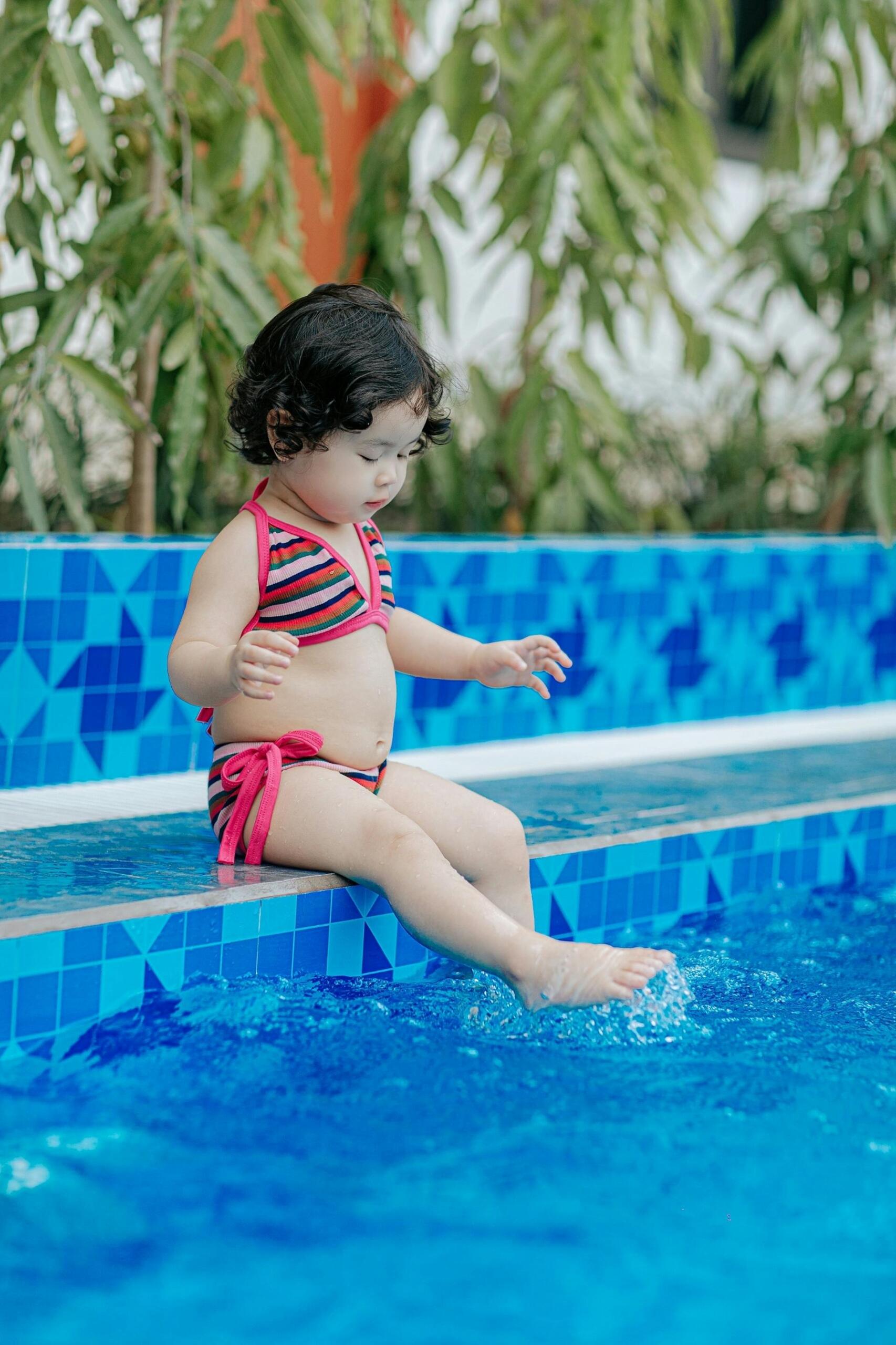 menina sentada na beira da piscina
