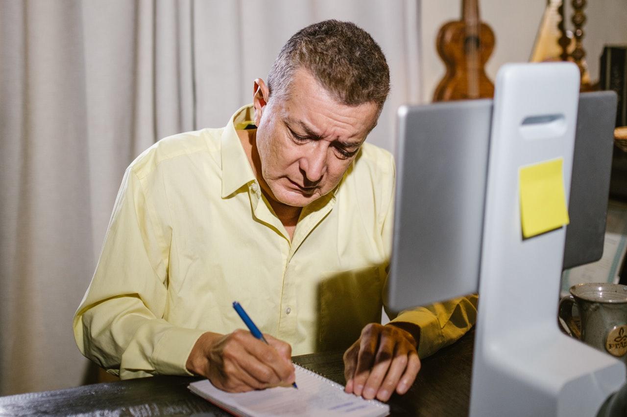 homem a tirar notas com visor computador