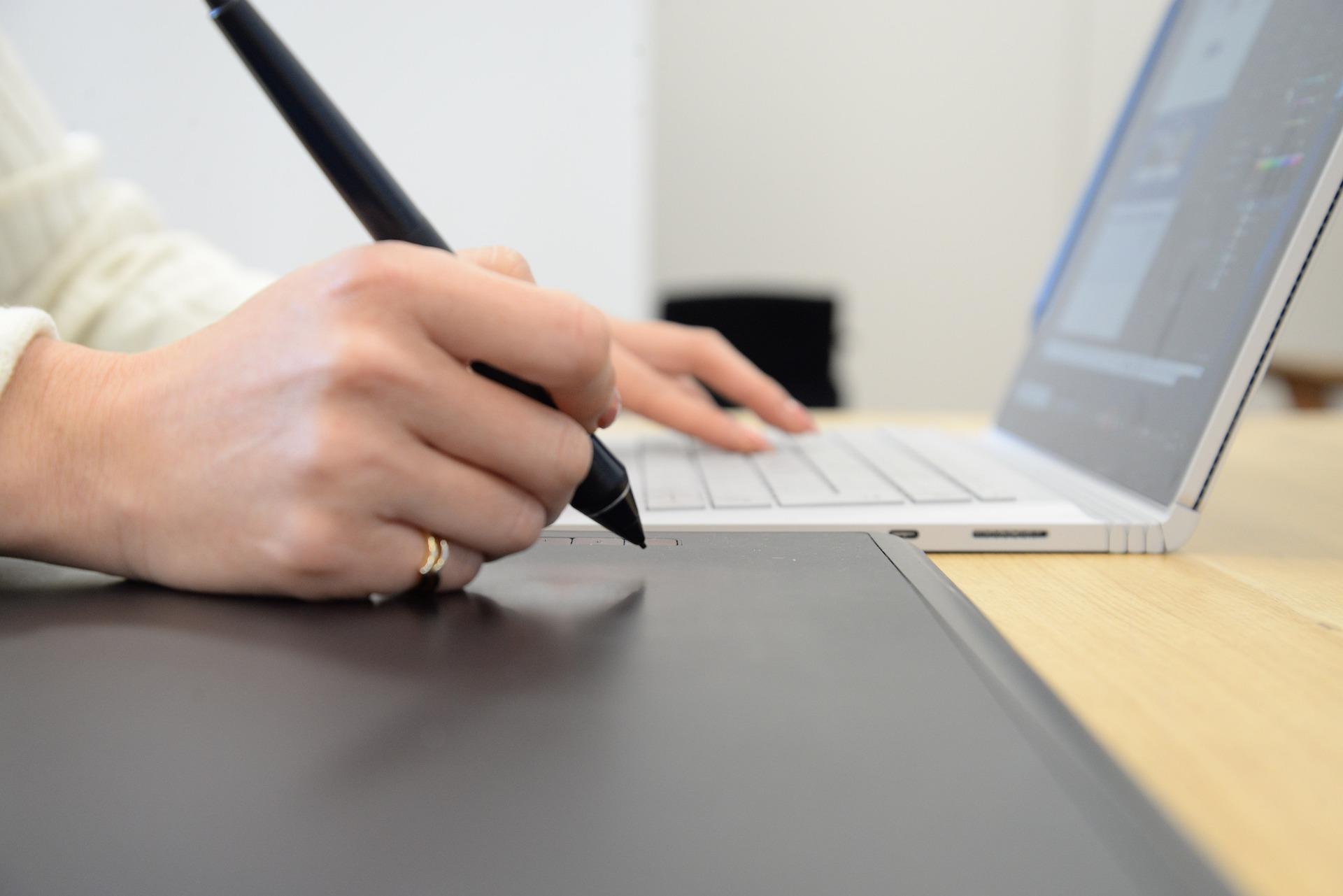 Mulher com computador portátil e caneta de desenho