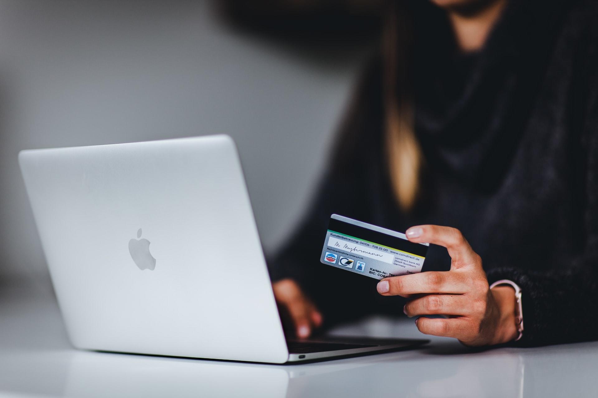 Computador e mulher com cartão bancário na mão