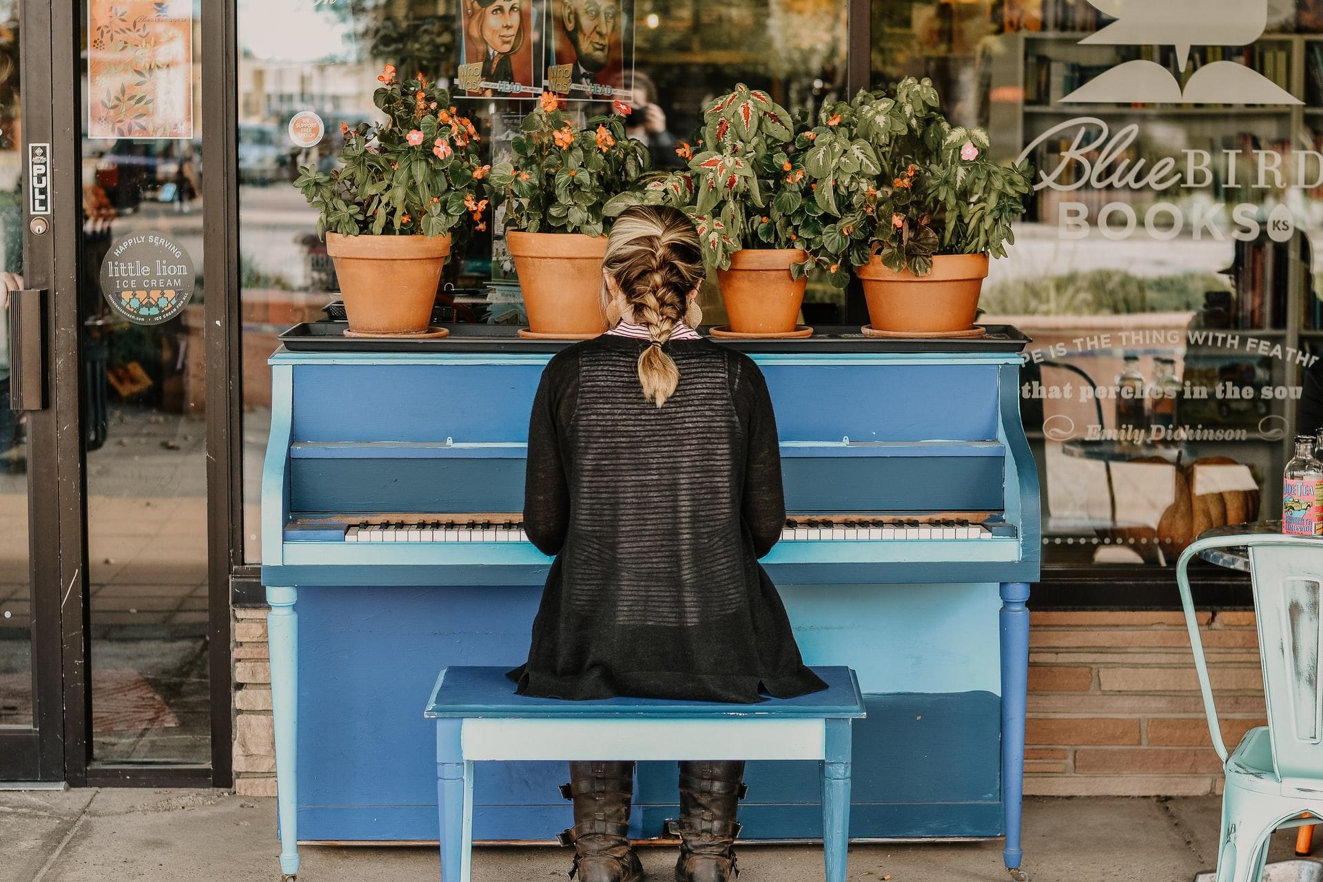 Mulher de costas a tocar no piano azul