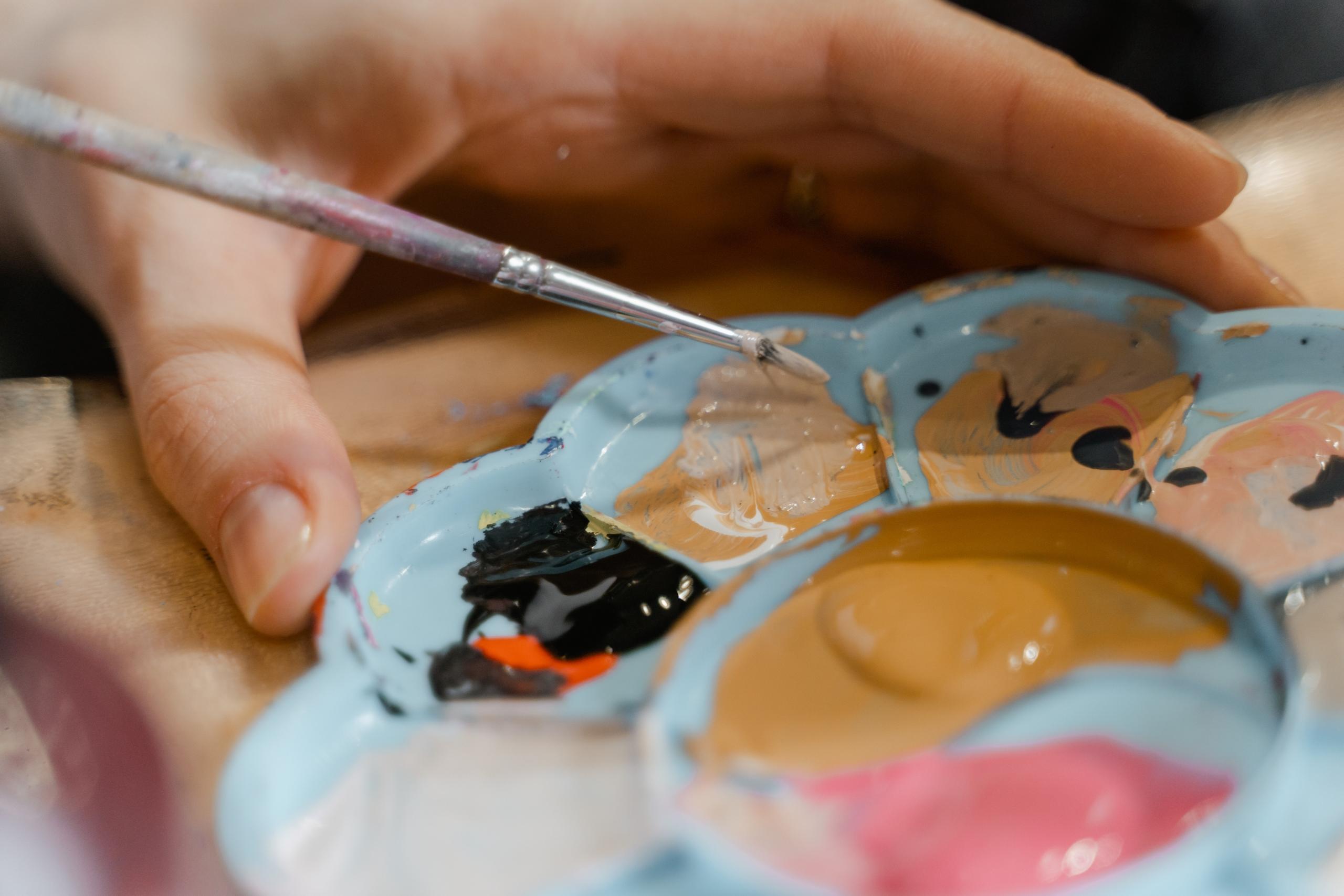 Mão com pincel e palete de tintas